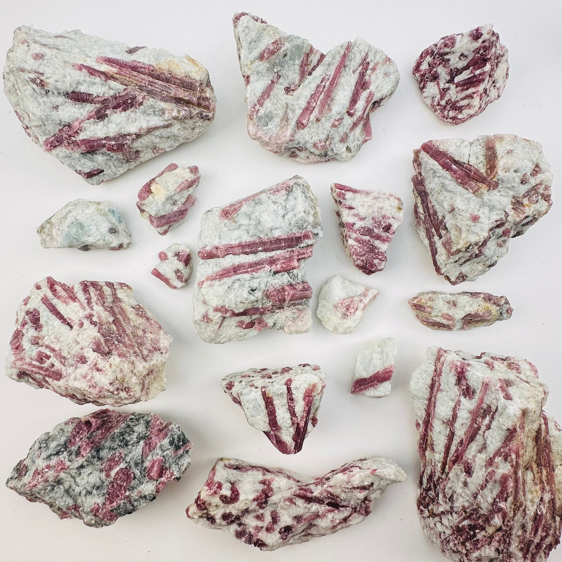 multiple pink tourmaline crystal clusters displayed to show the differences in the size and color shades 