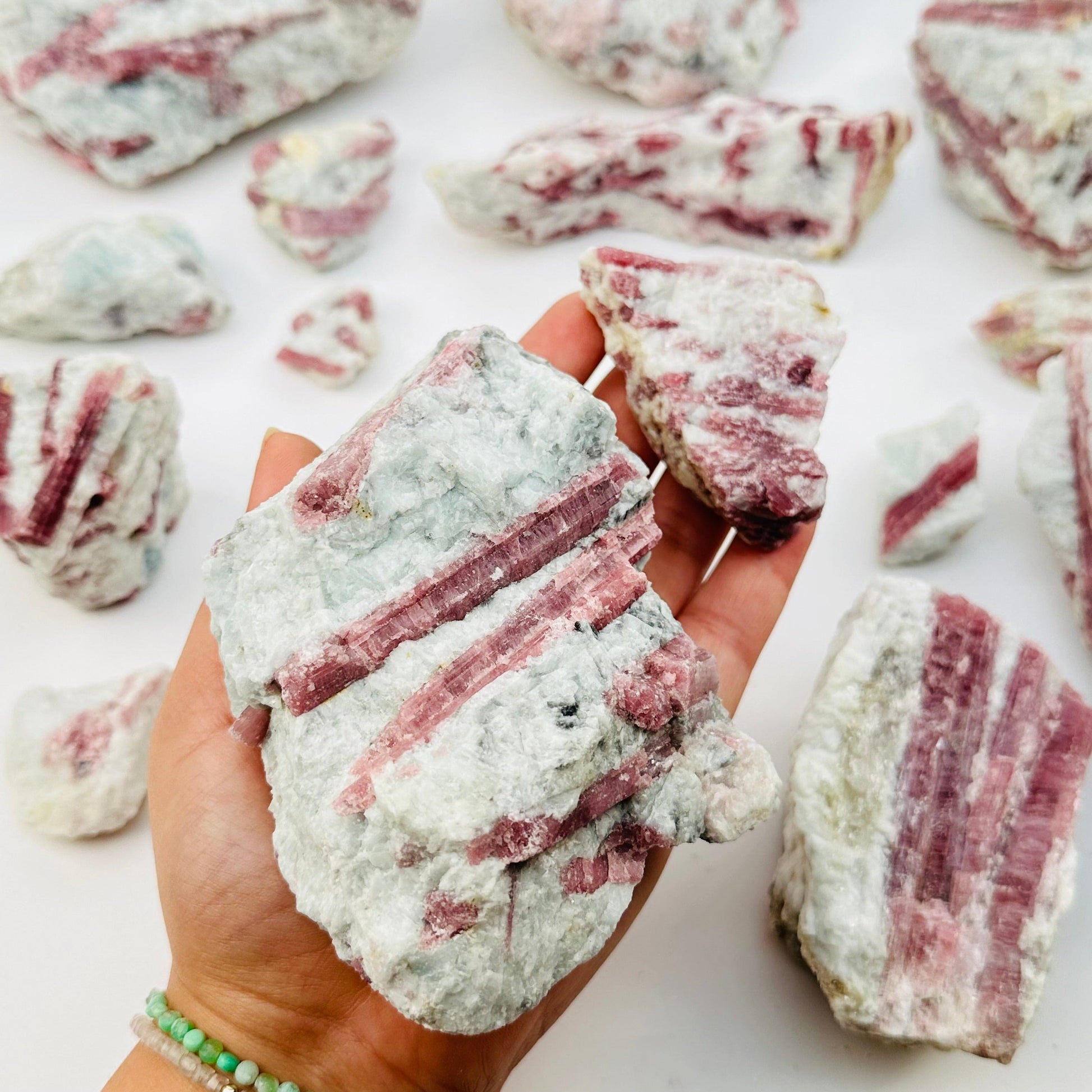 pink tourmaline crystal clusters in hand for size reference 