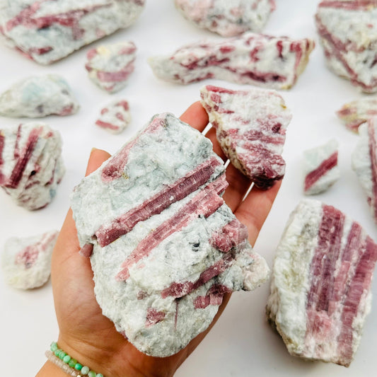 pink tourmaline crystal clusters in hand for size reference 