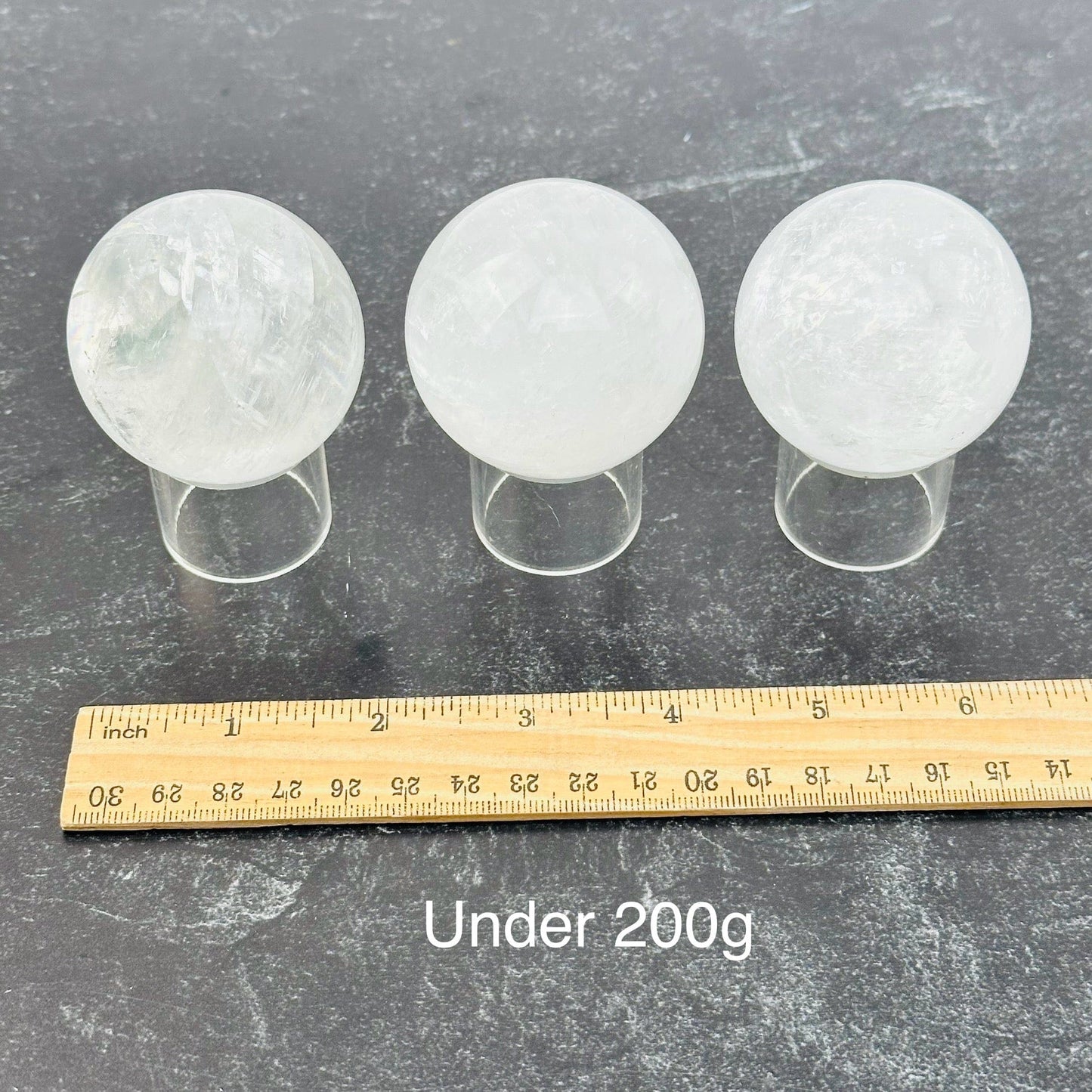 calcite crystal spheres sold by the weight. displayed next to a ruler for size reference 