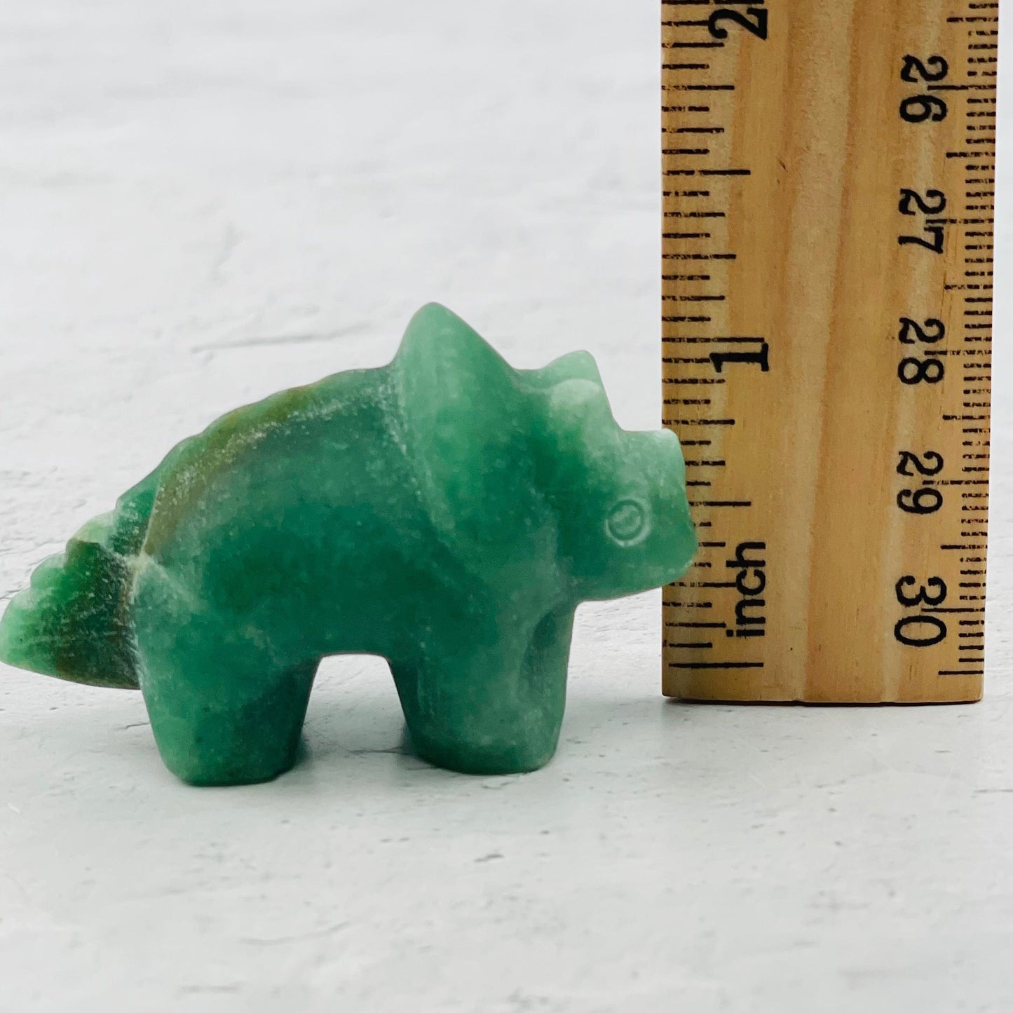 carved dinosaur next to a ruler for size reference 