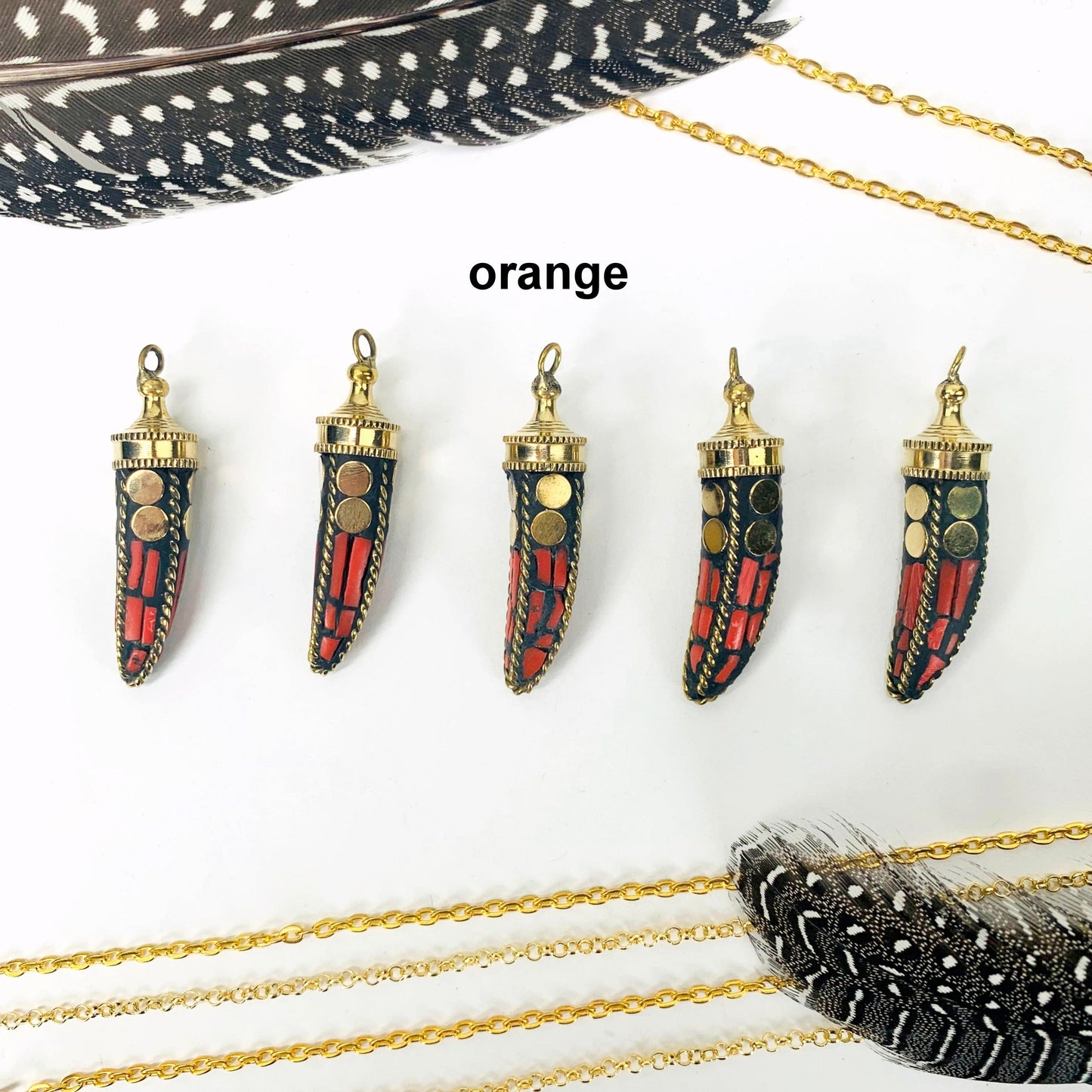 overhead view of five orange petite mosaic horn pendants in a row on white background with decorations for possible variations