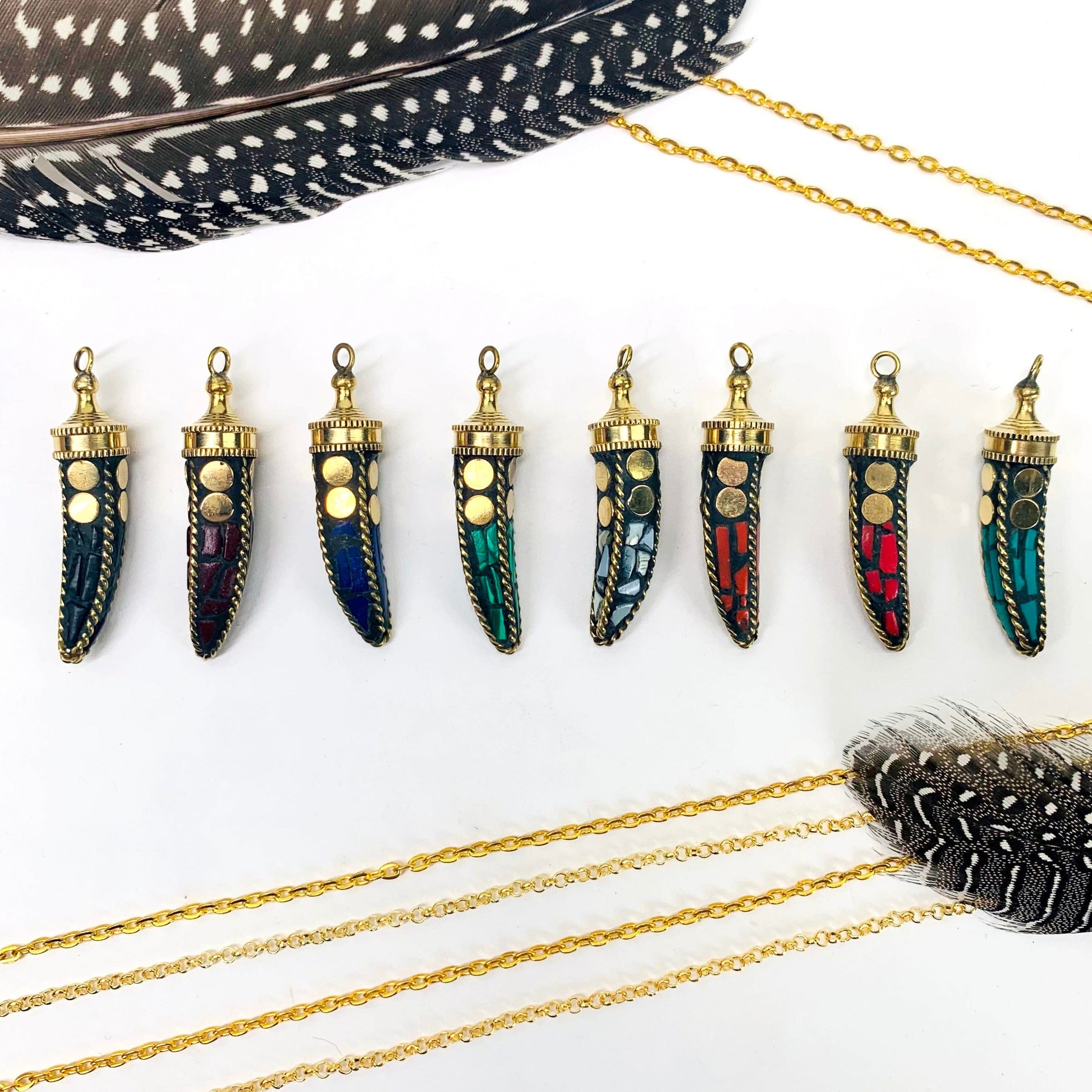 overhead view of one of each petite mosaic horn pendant color options in a row on white background with decorations