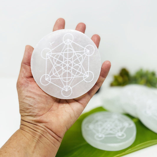 selenite round with metatron engraving in hand for size reference