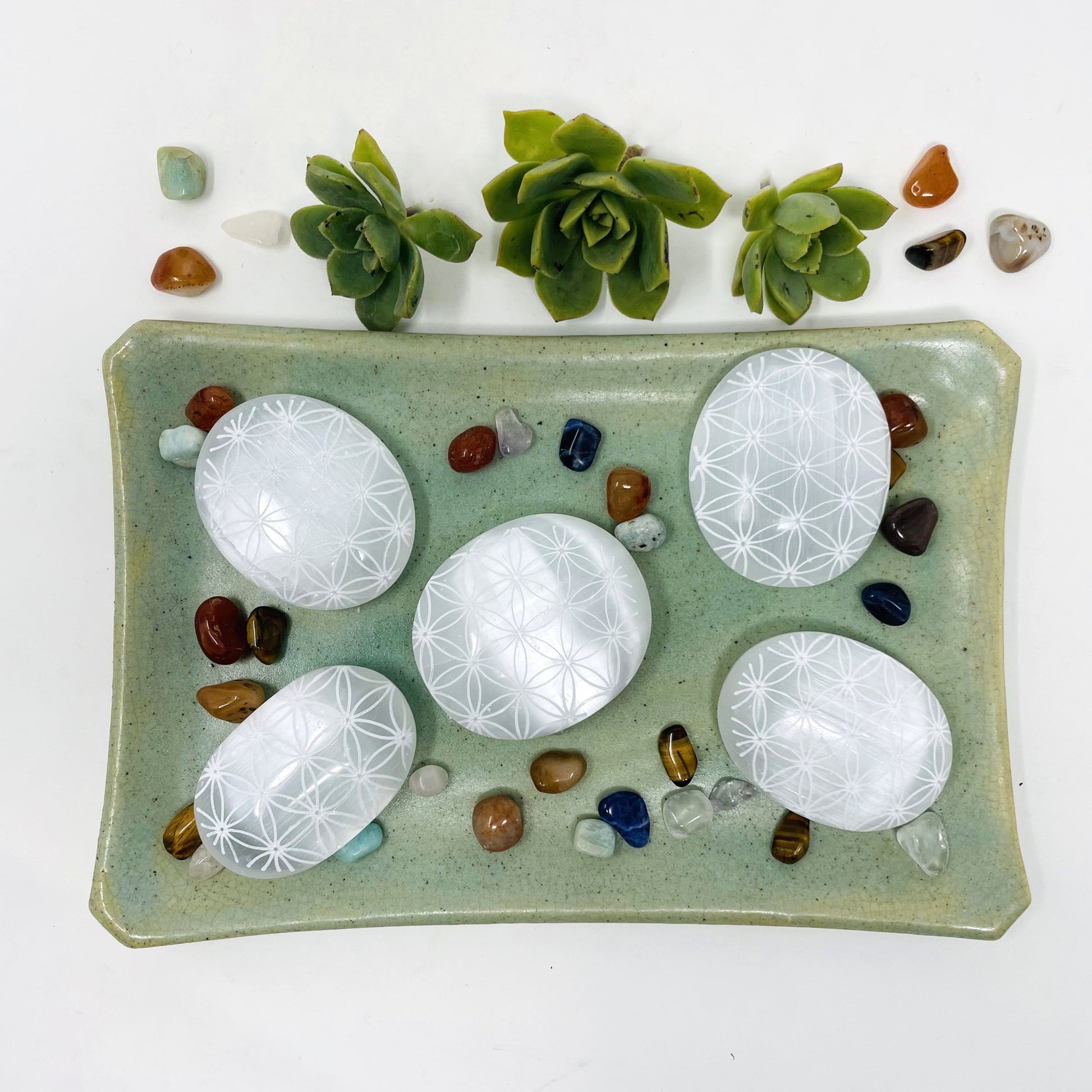 overhead view of selenite flower of life engraved palm stones on display for possible variations 