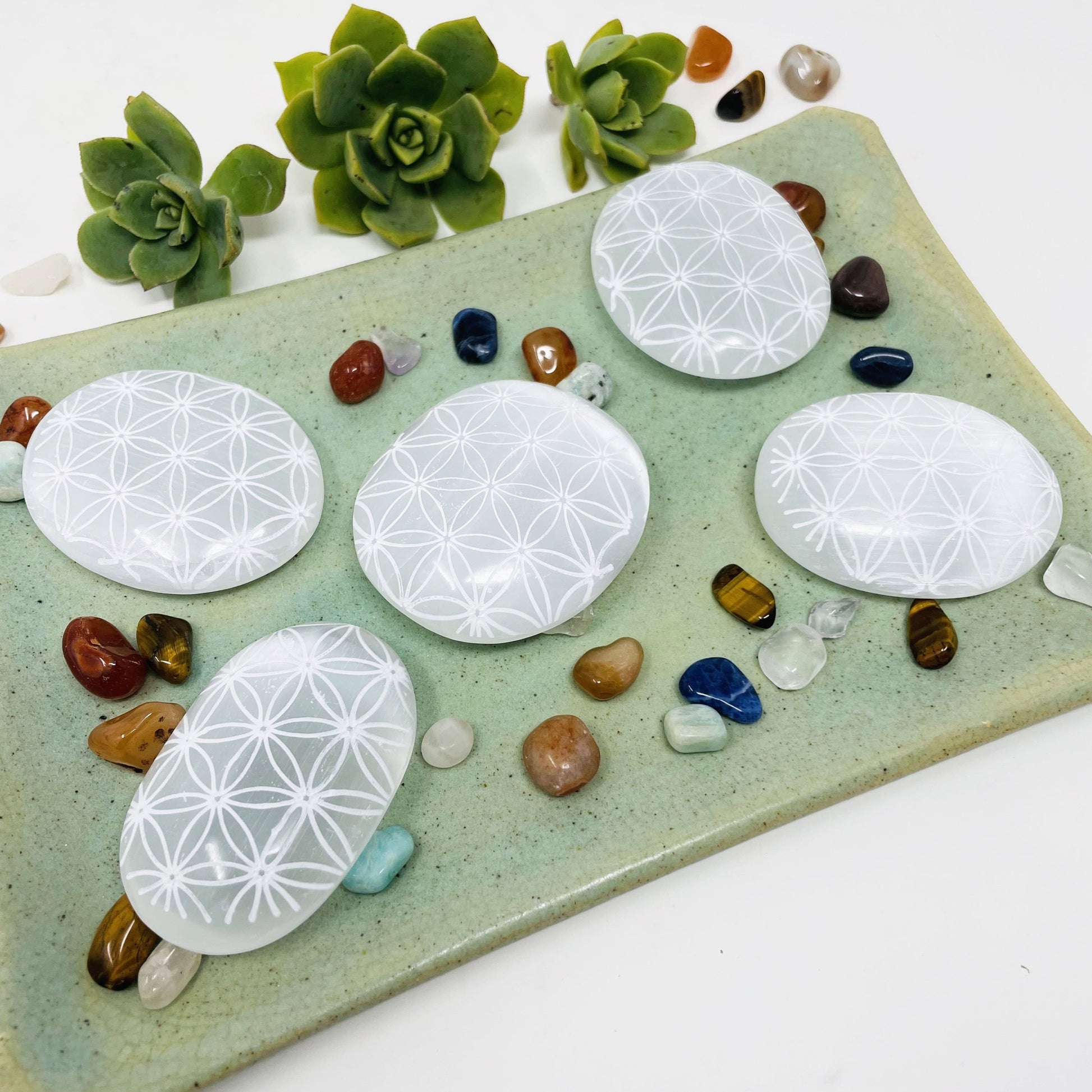 selenite flower of life engraved palm stones on display