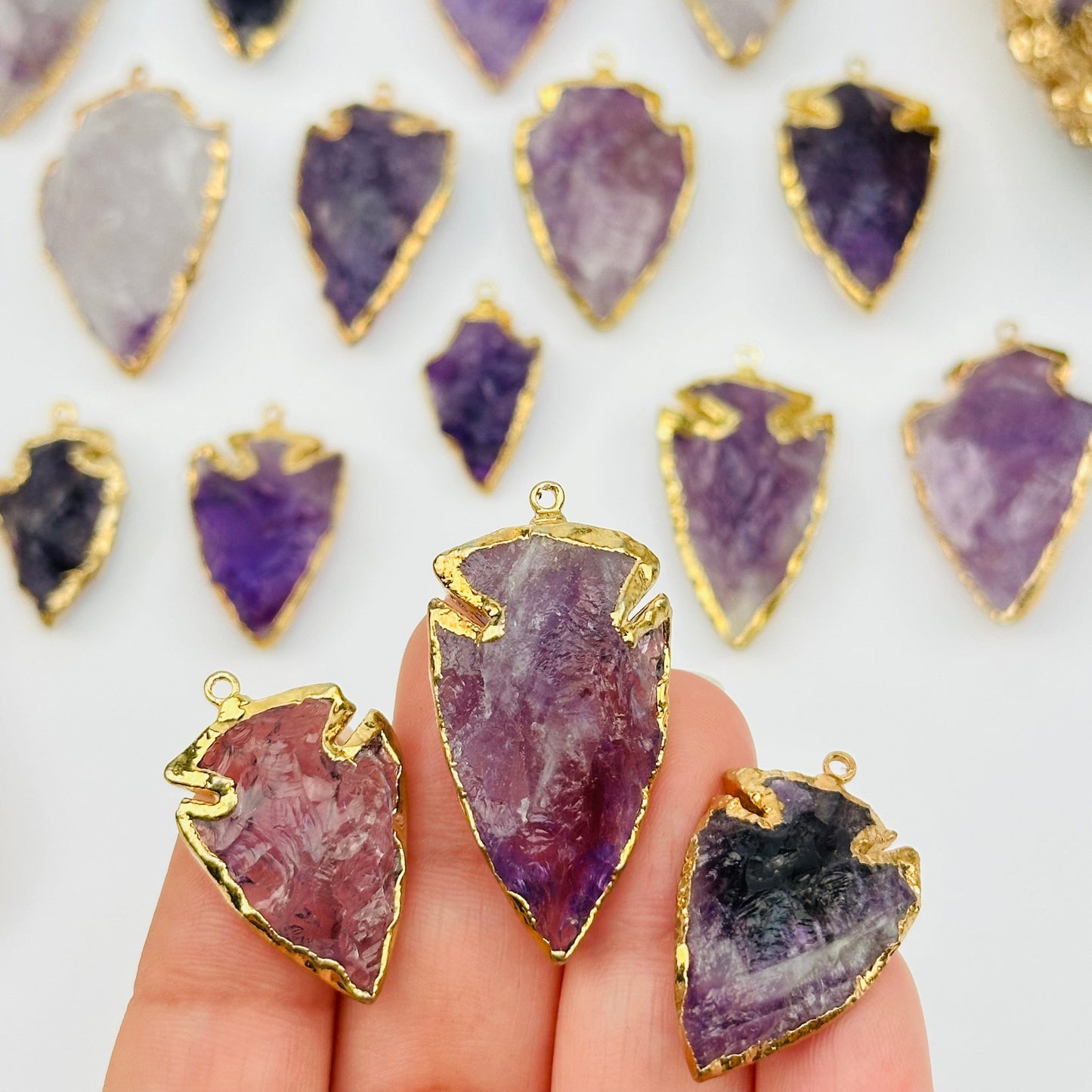 amethyst arrowhead pendant charm with 24k gold electroplated edges on hand for size reference 