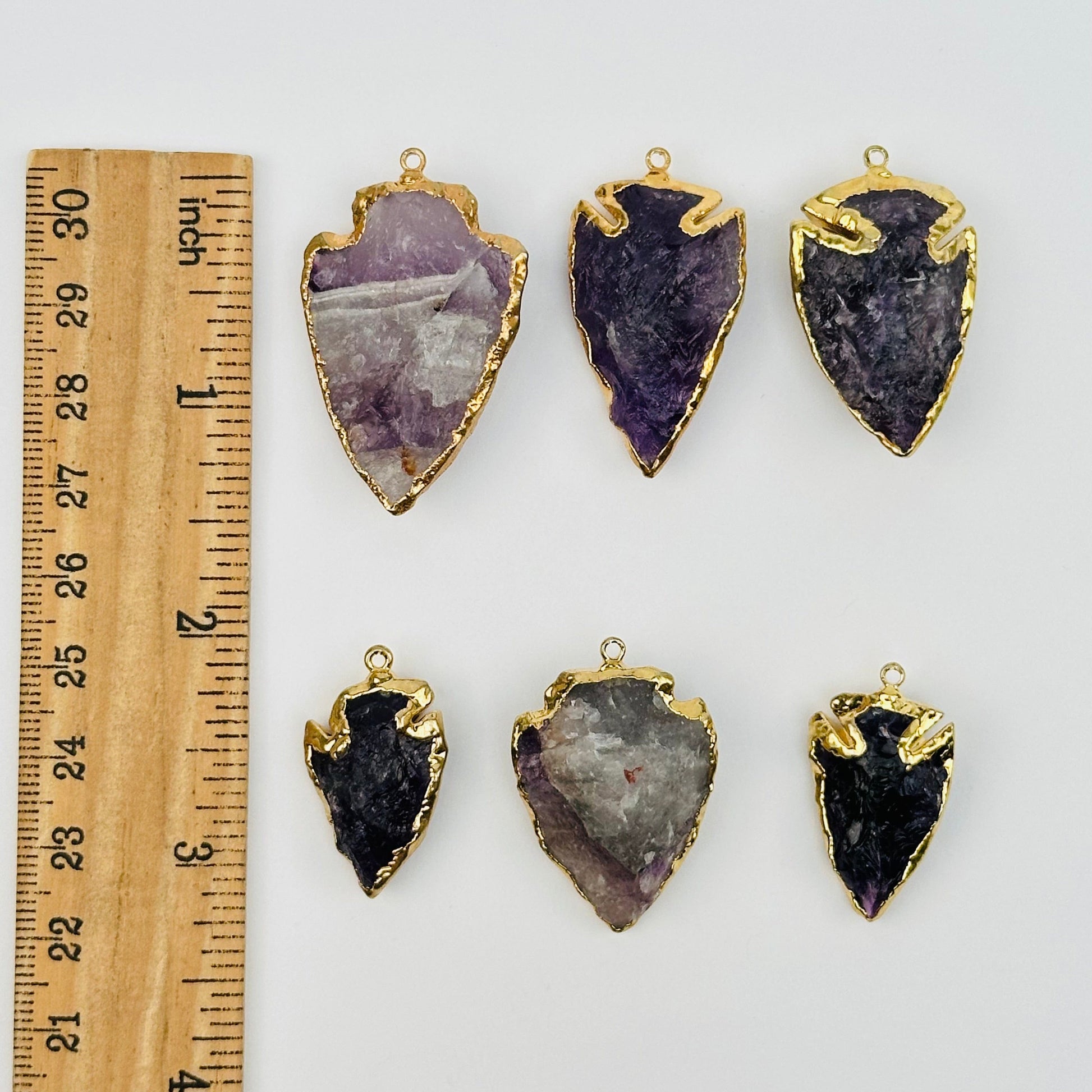 amethyst arrowhead pendant charm with 24k gold electroplated edges Next to a ruler for size reference 