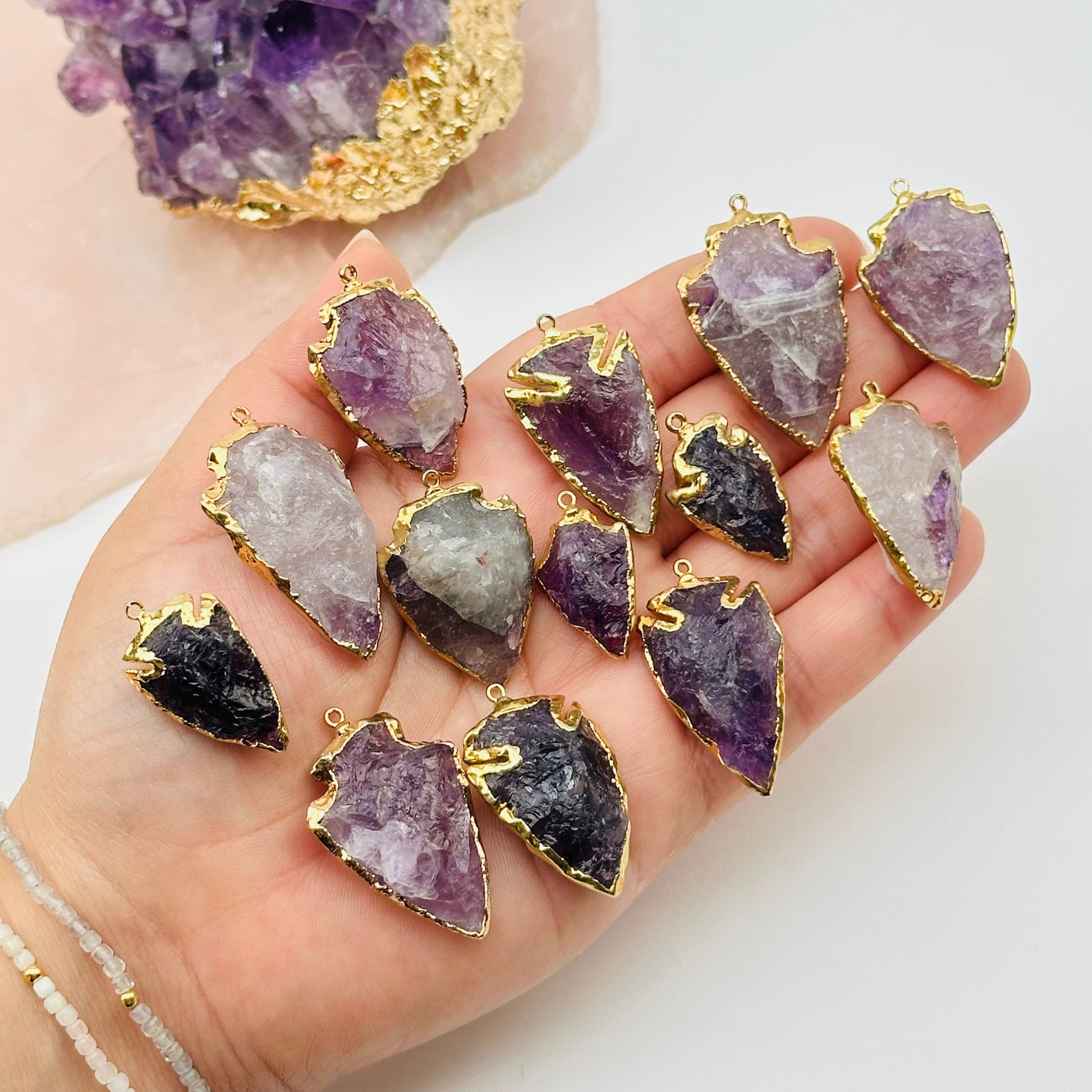 amethyst arrowhead pendant charm with 24k gold electroplated edges on hand for size reference 