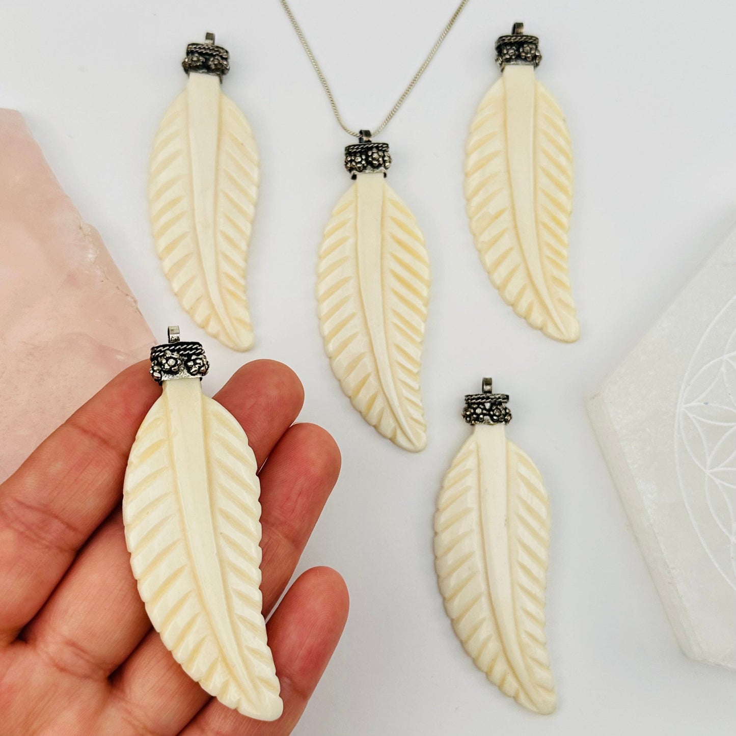 carved bone feather on hand for size reference