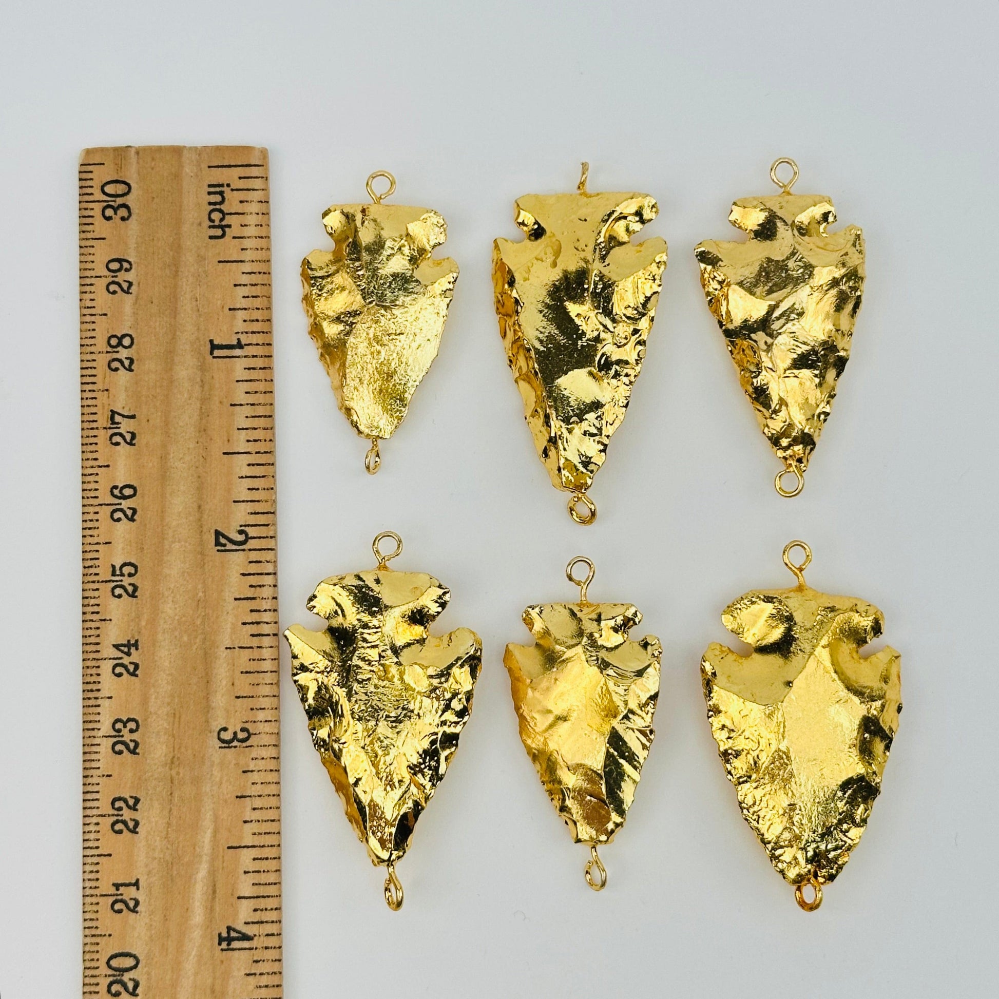 double bail arrowhead charms next to a ruler for size reference 