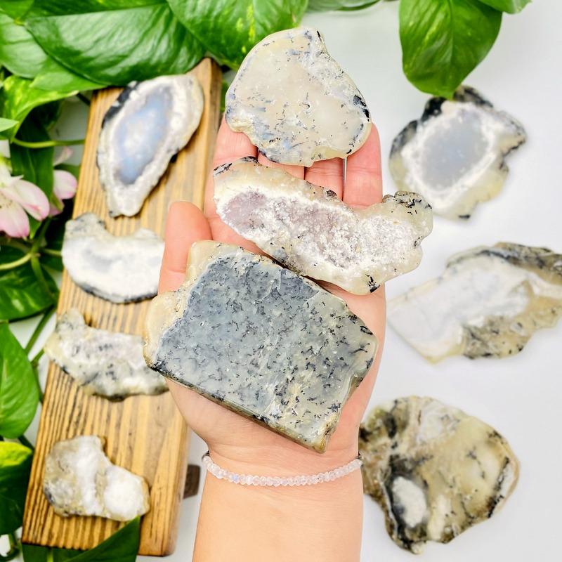 3 Dendritic Opal Slabs in Hand for Size Reference on White Background.