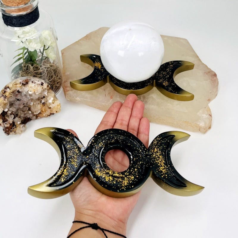 black and gold sphere stand in hand for size reference 