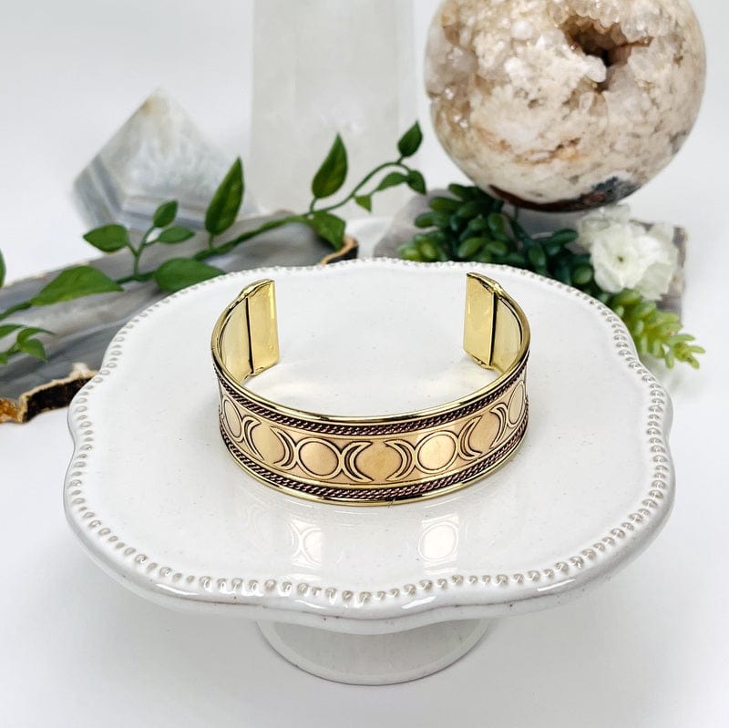 triple moon phase brass bracelet with a copper twist accent on the top and bottom of the cuff 