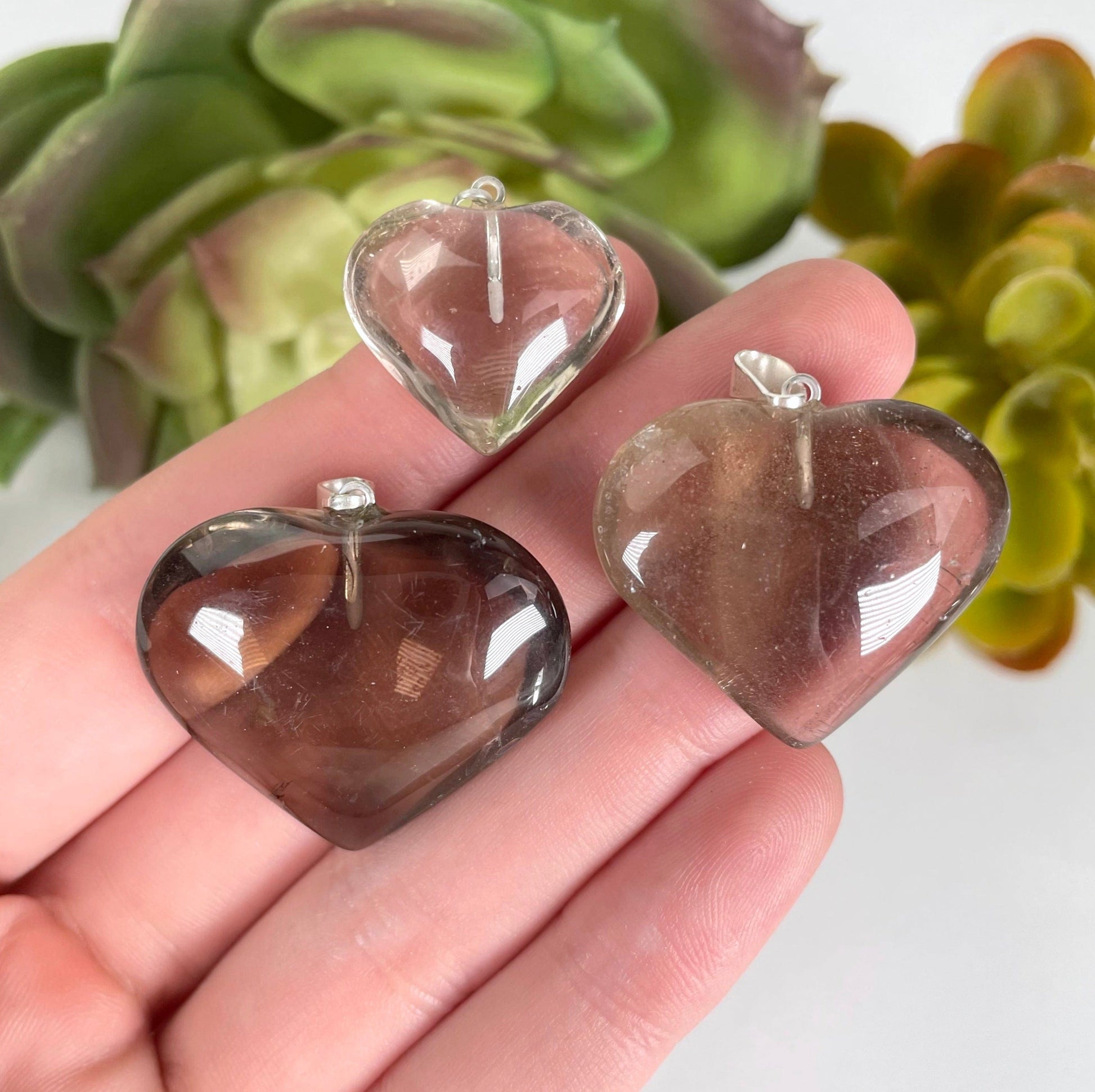 three natural citrine heart pendants in hand for size reference and possible variations