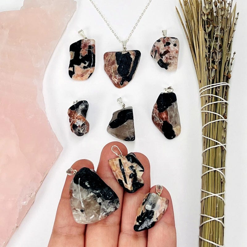 black tourmaline and feldspar pendants in hand for size reference 