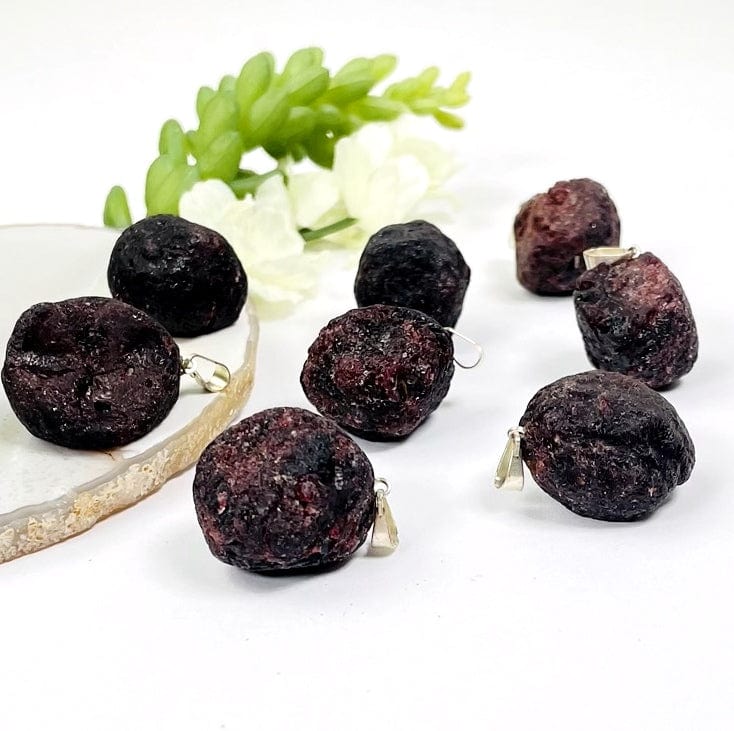 rough garnet with silver bail on a table