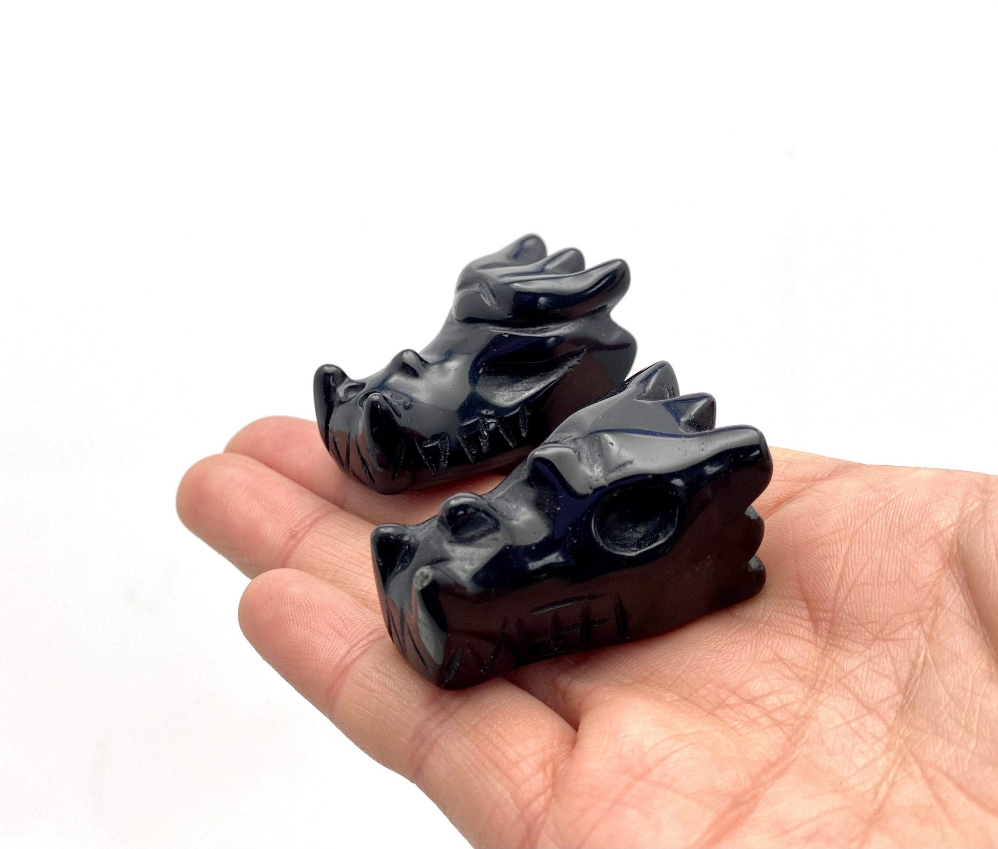 Black Onyx Dragon Head Mini Statues in Hand on White Background.