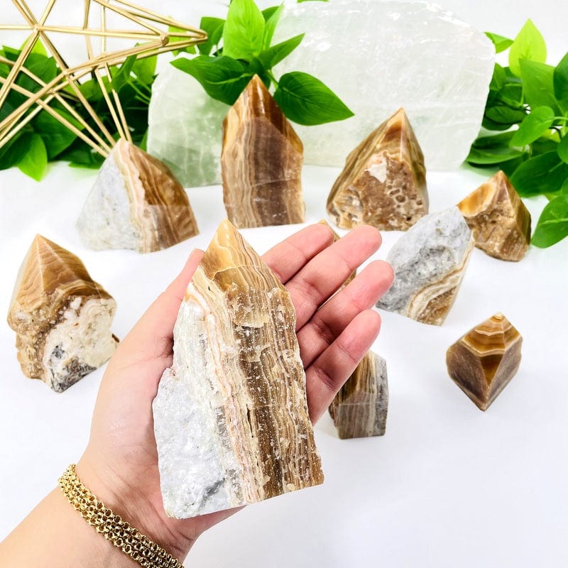 high grade aragonite semi polished point in hand showing size 