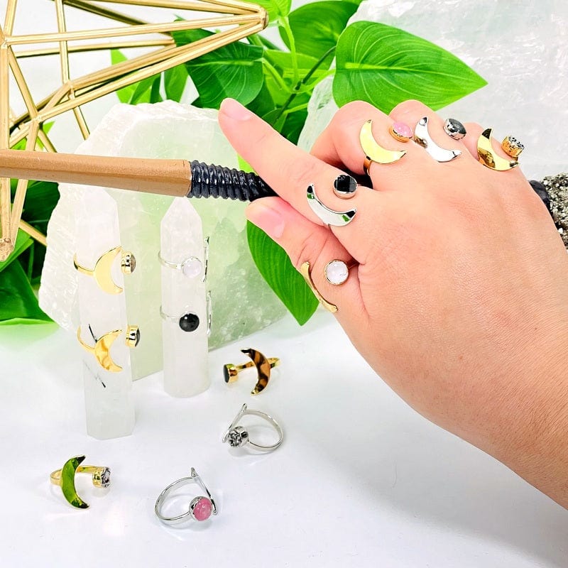 multiple moon rings with gemstone accents in gold and silver on hand 