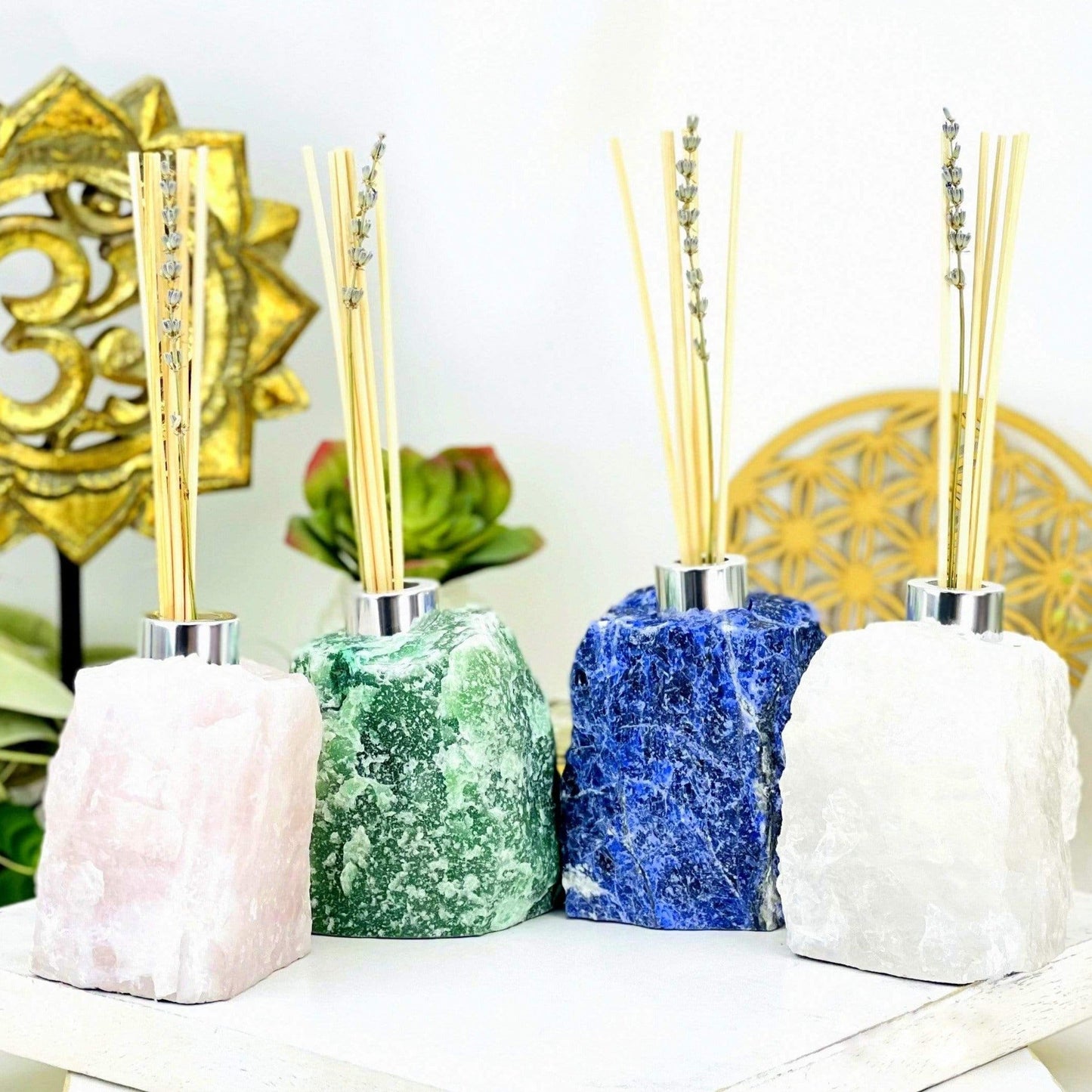 4 Rough Stone Diffuser Bottles of different crystals with decorations in the background