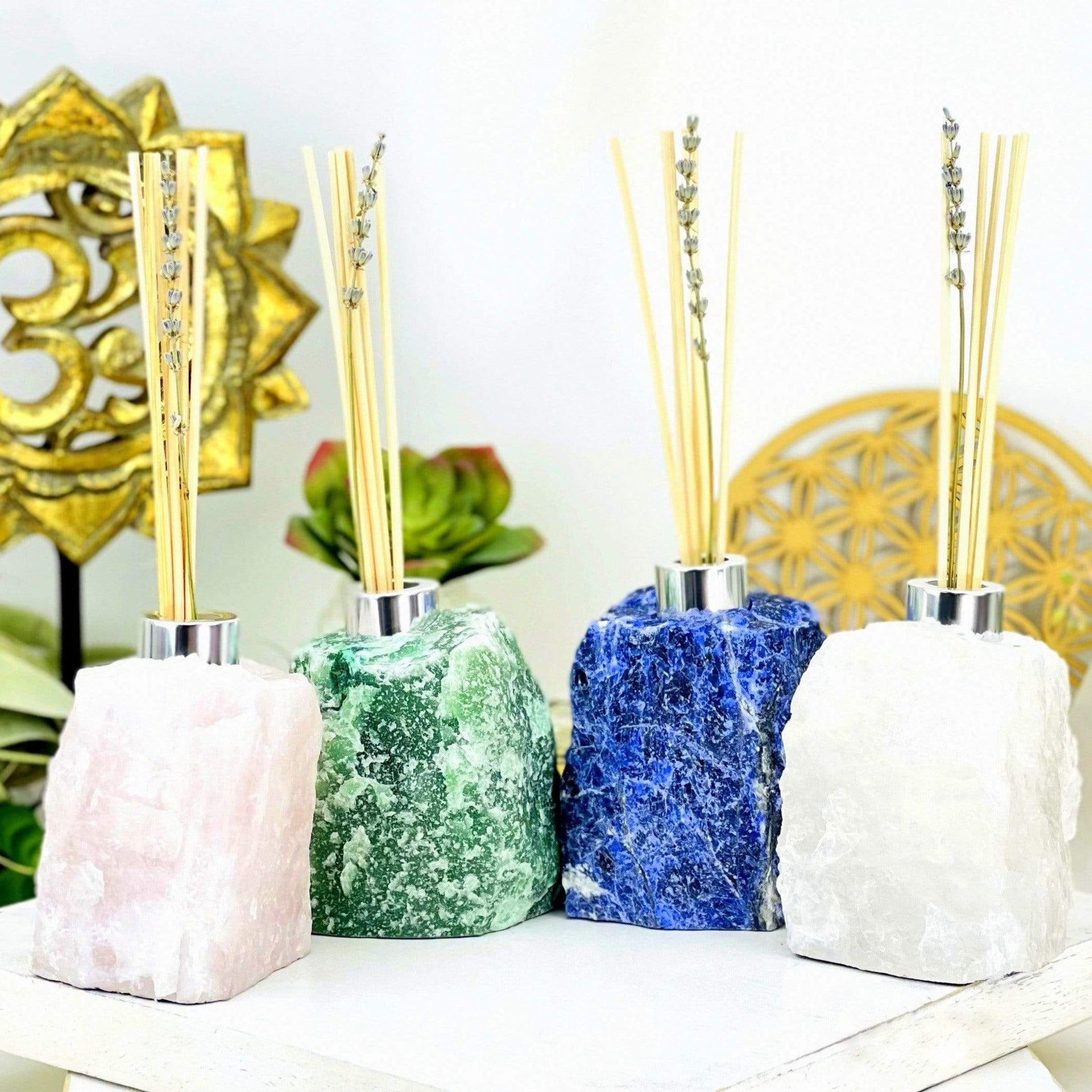 4 Rough Stone Diffuser Bottles of different crystals with decorations in the background
