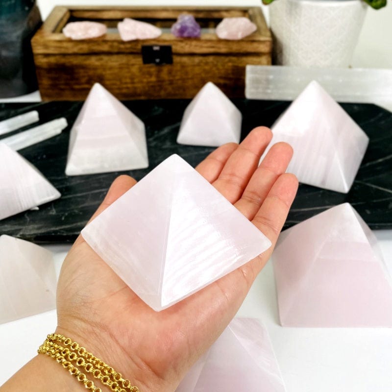 pink calcite pyramid in hand for size reference 