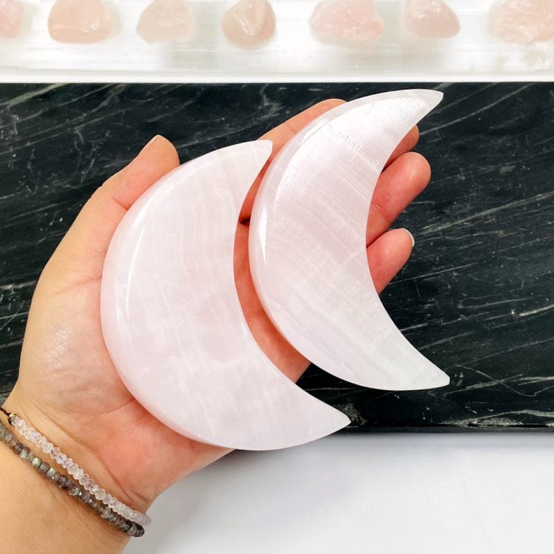 pink calcite moons in hand showing size 