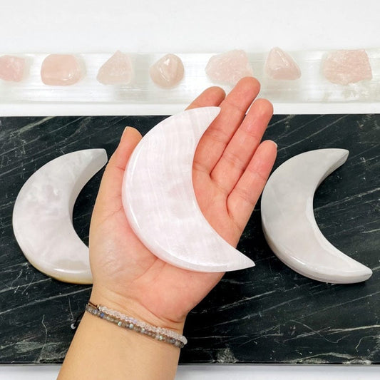 pink calcite moon in hand for size reference 