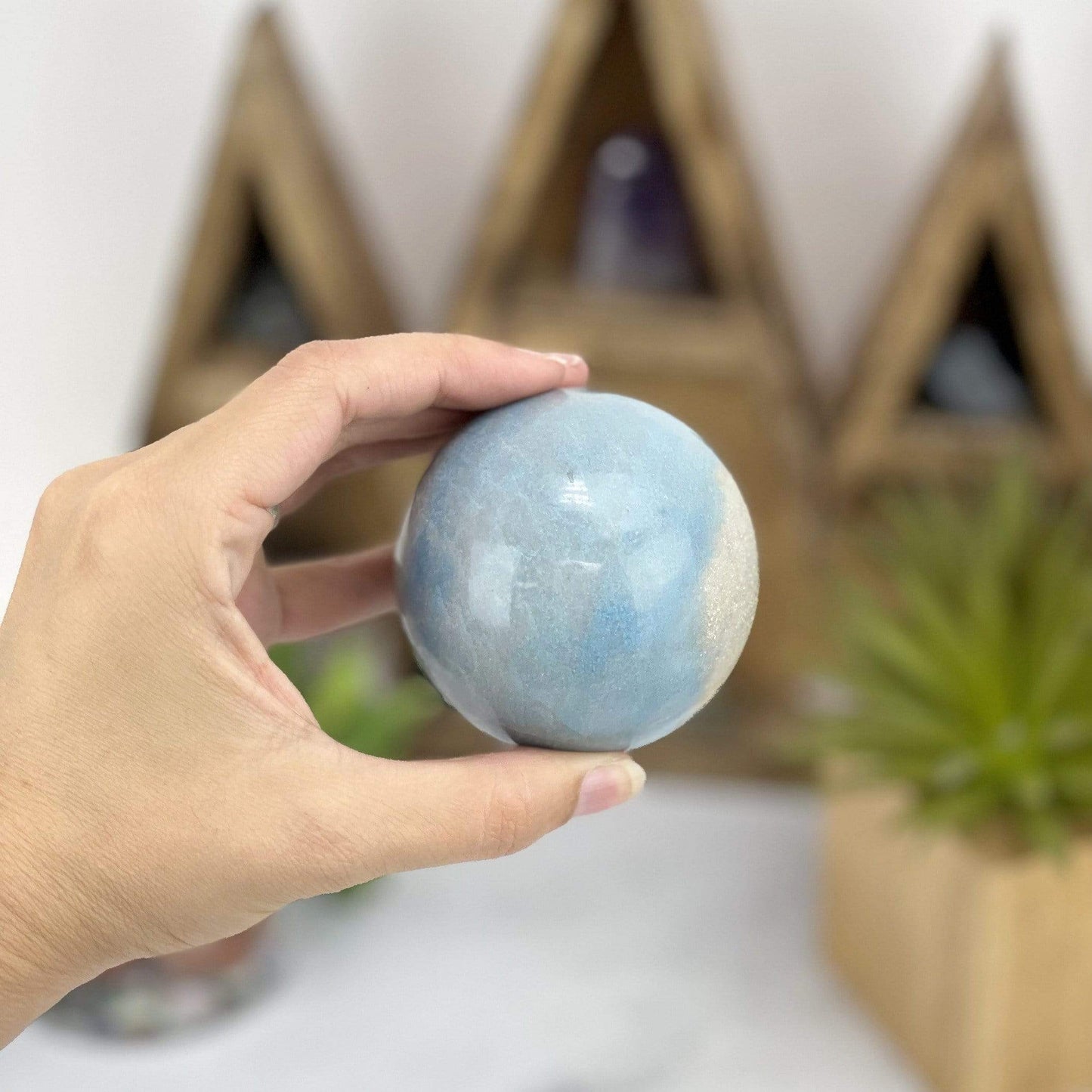 hand holding up Trolleite Sphere with decorations in the background