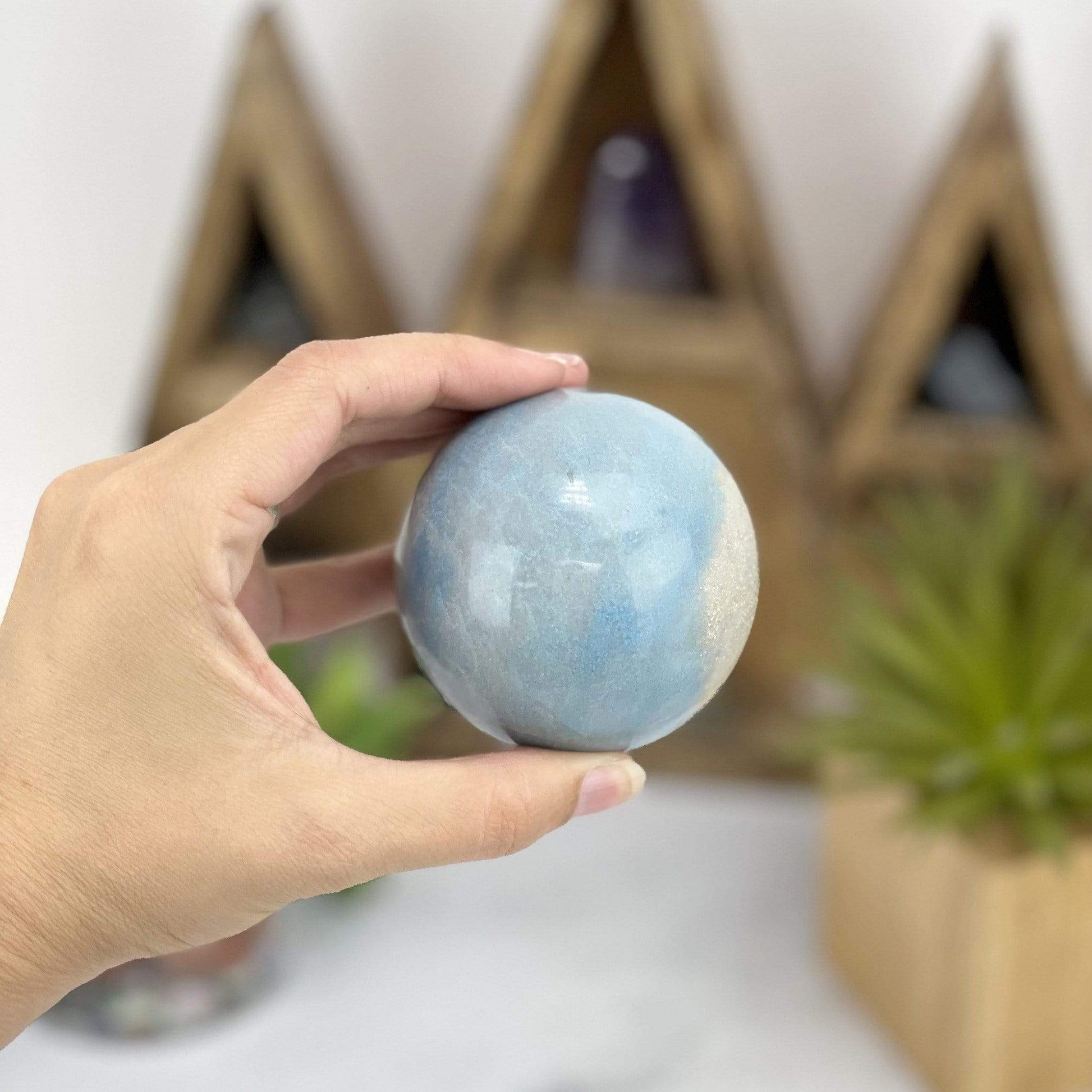hand holding up Trolleite Sphere with decorations in the background