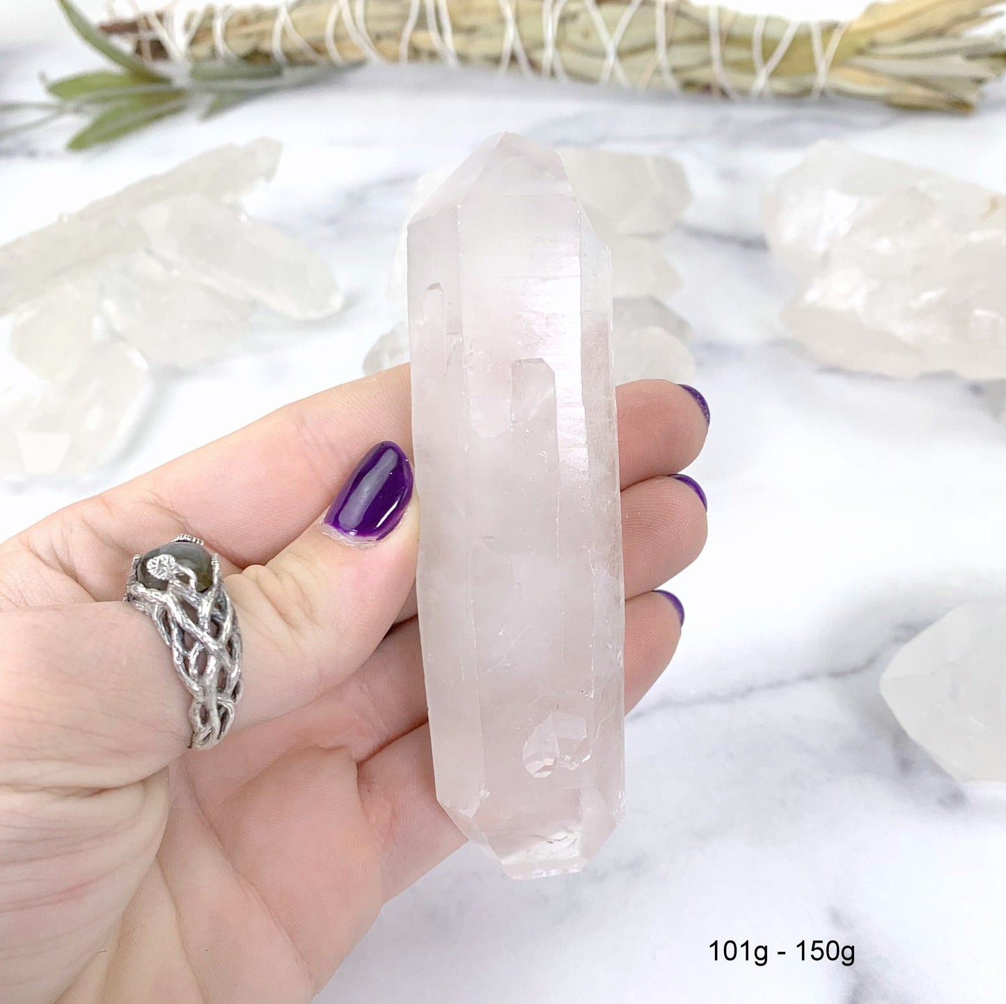 101gram - 150 gram lemurian quartz in hand with marble background