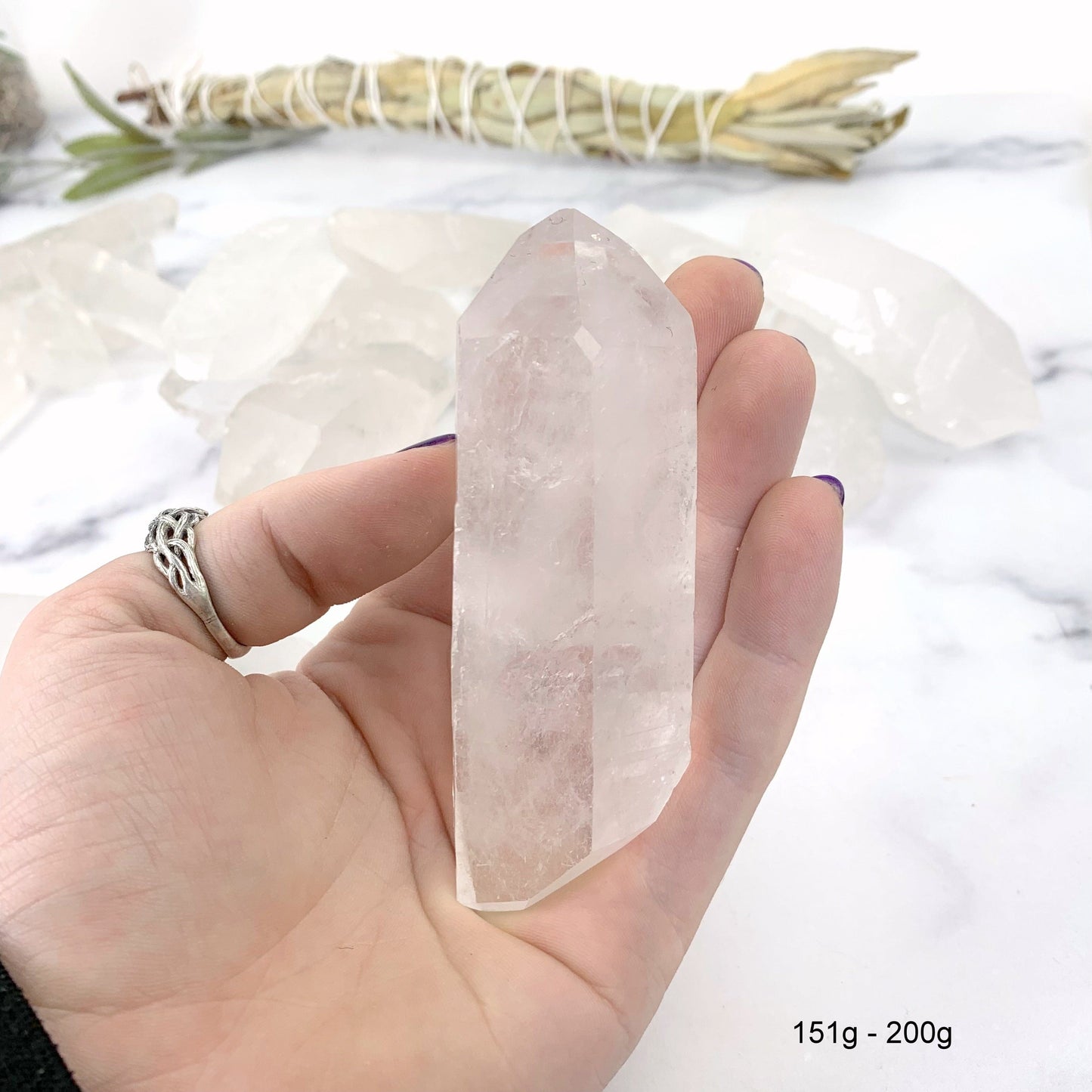 151gram - 200 gram lemurian quartz in hand with marble background