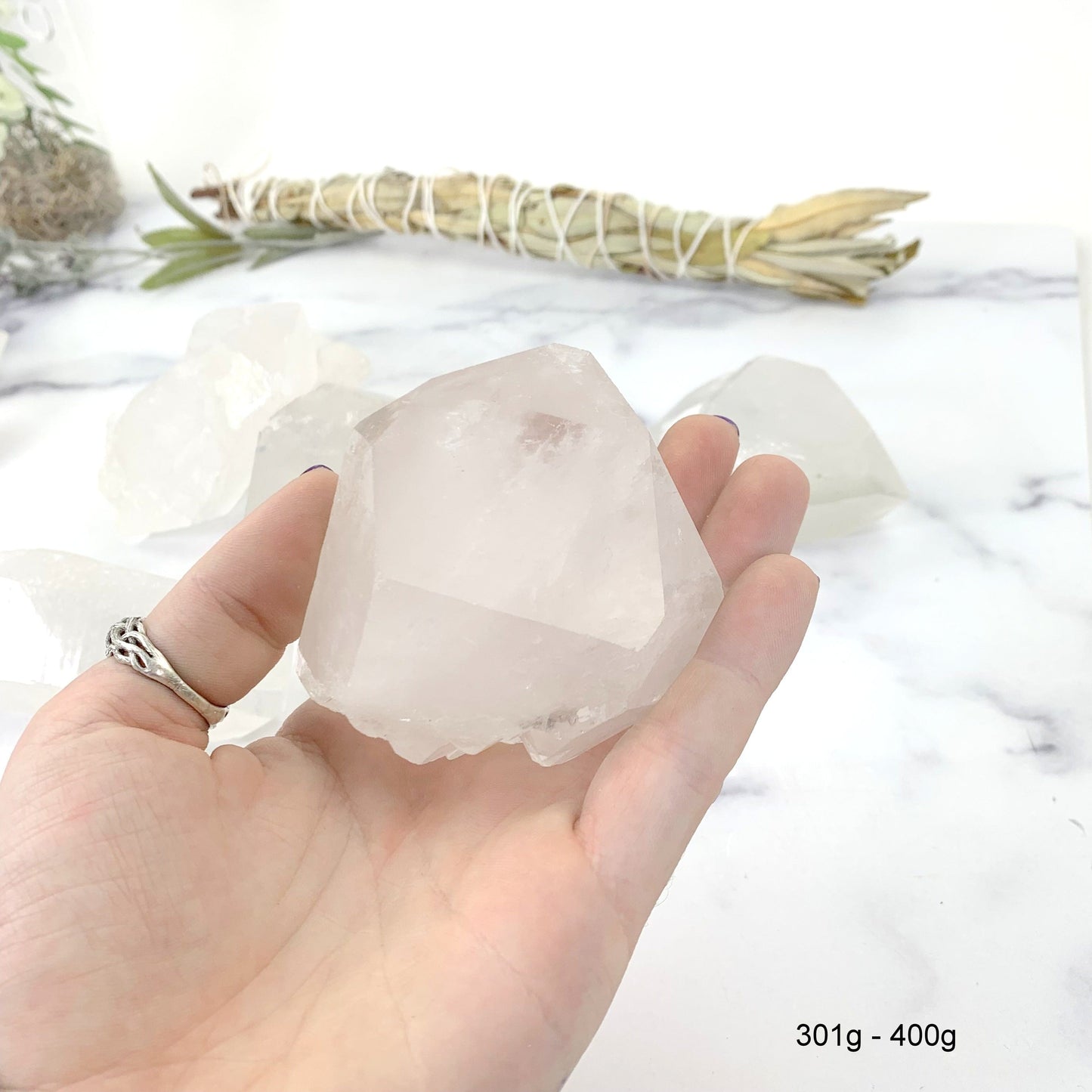 301gram - 400 gram lemurian quartz in hand with marble background