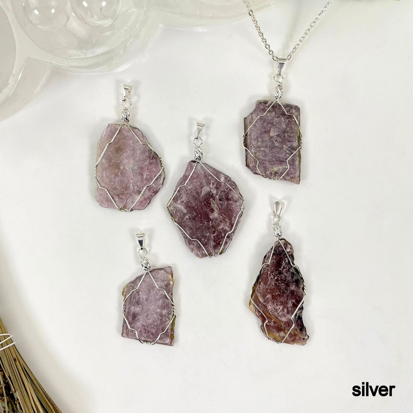 overhead view of six silver purple mica wire wrapped pendants on white background with one strung on silver chain for possible variations