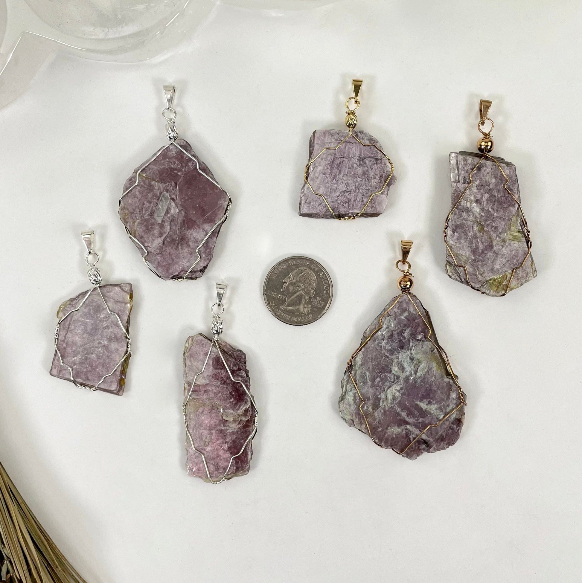 overhead view three gold and three silver purple mica wire wrapped pendants on white background with a quarter for size reference