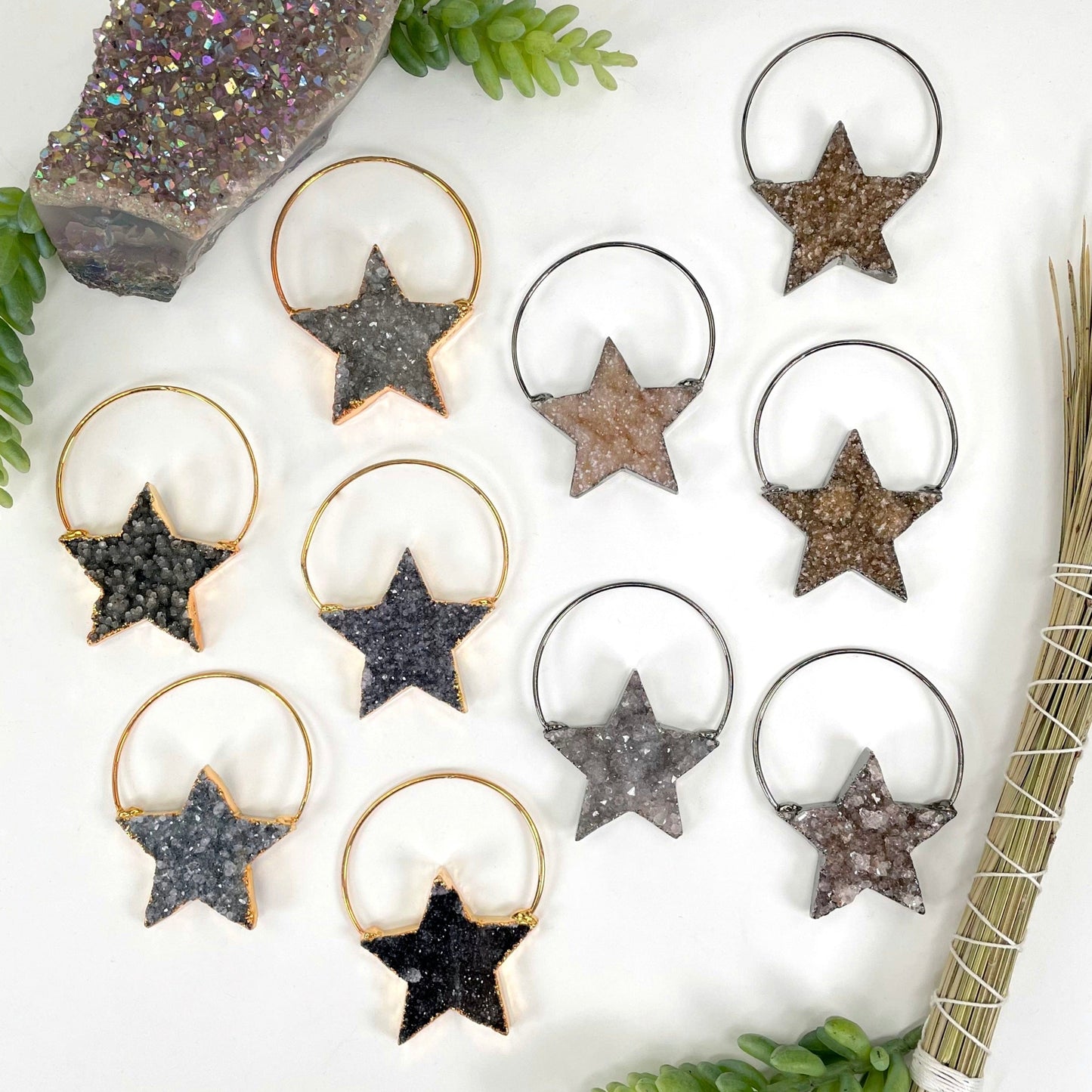 overhead view of many gold and gunmetal druzy star pendants on display on white background for possible variations 