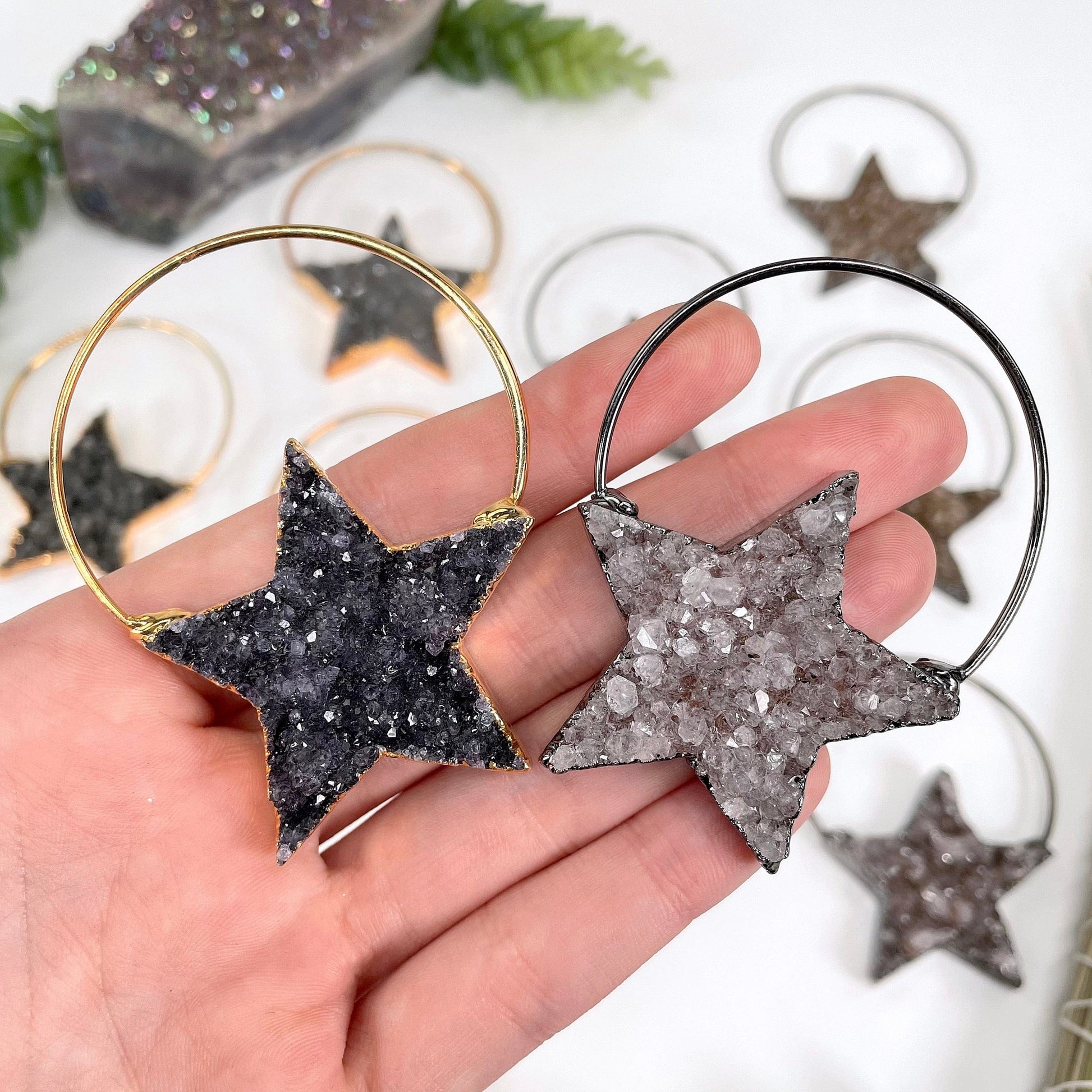 close up of one gold and one gunmetal druzy star pendant in hand for possible variations and size reference