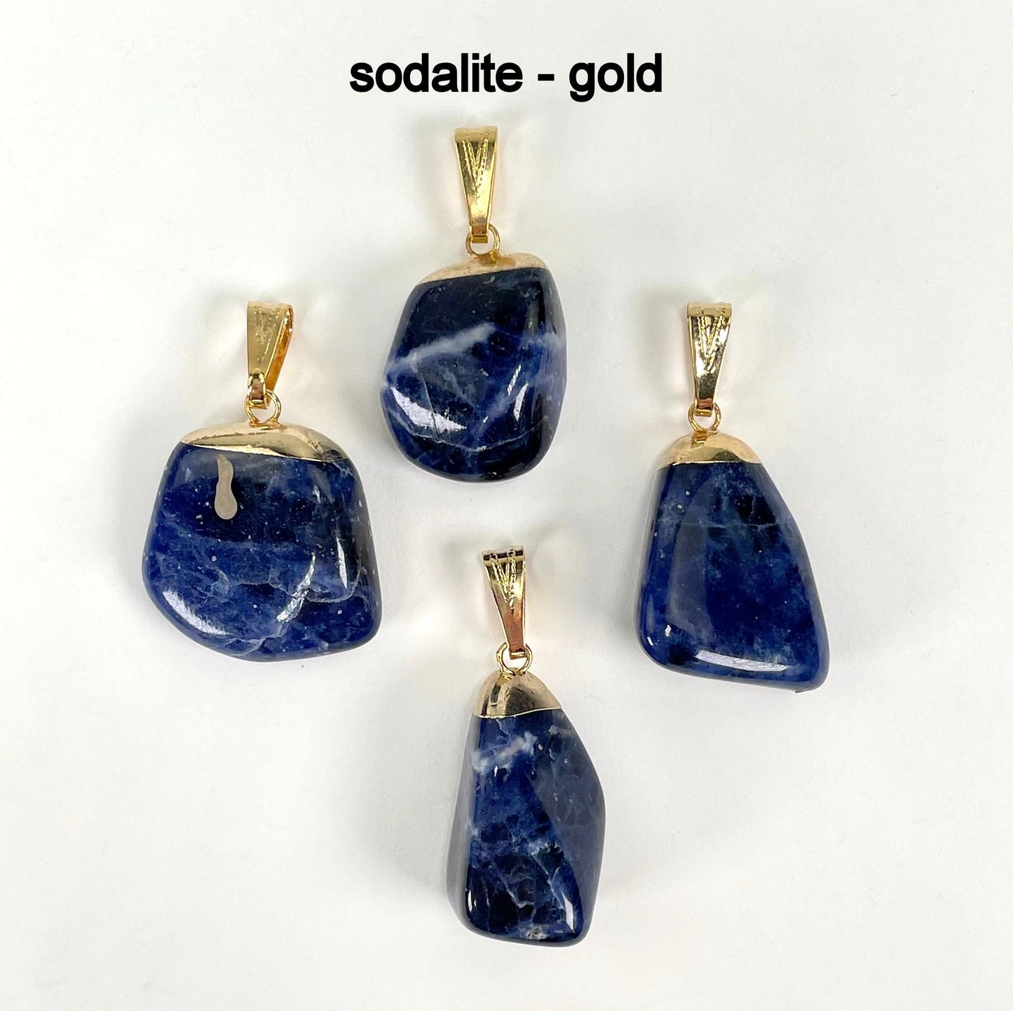 close up of four tumbled sodalite pendants in gold for possible stone variations and details