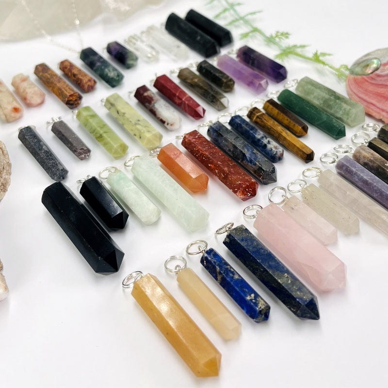 multiple gemstone pendants with with silver toned bails displayed showing the differences in the stone colors and sizes
