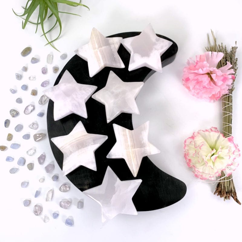 7 pink calcite stars on a black moon with a white background