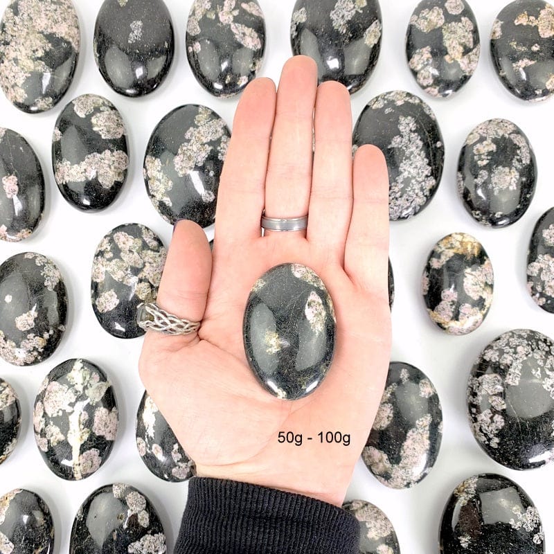 50 gram - 100 gram black jade with pink thulite palm stone in hand 