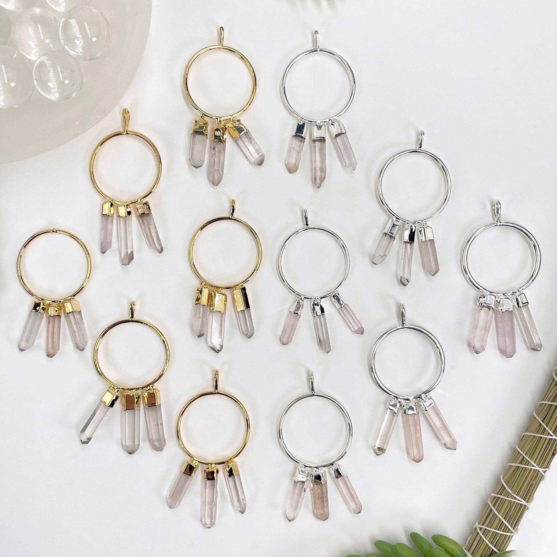 overhead view of many gold and many silver triple crystal point pendants on white background for possible variations