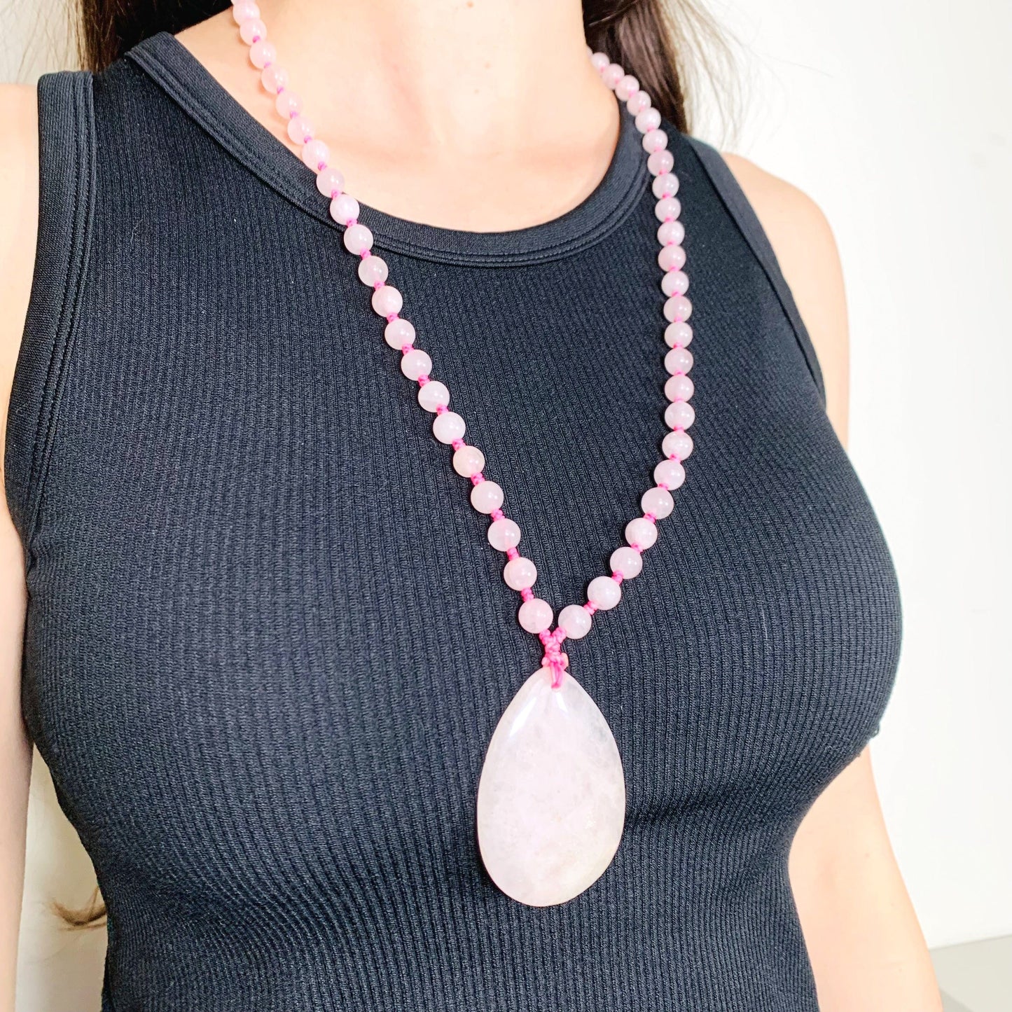 Left side angle of the Rose Quartz Tear Drop Pendant on Beaded Mala Necklace on model