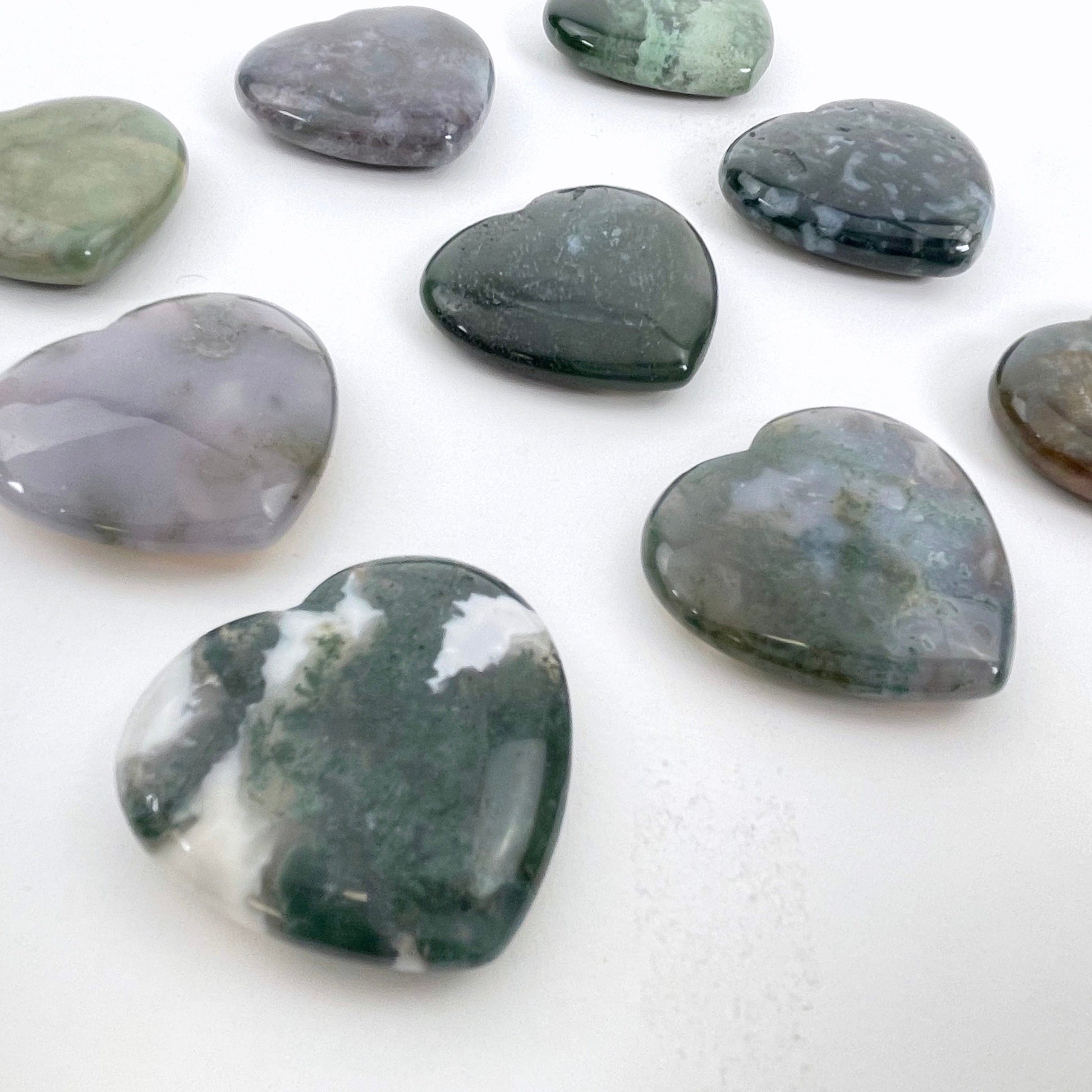 angled view of moss agate polished hearts for thickness