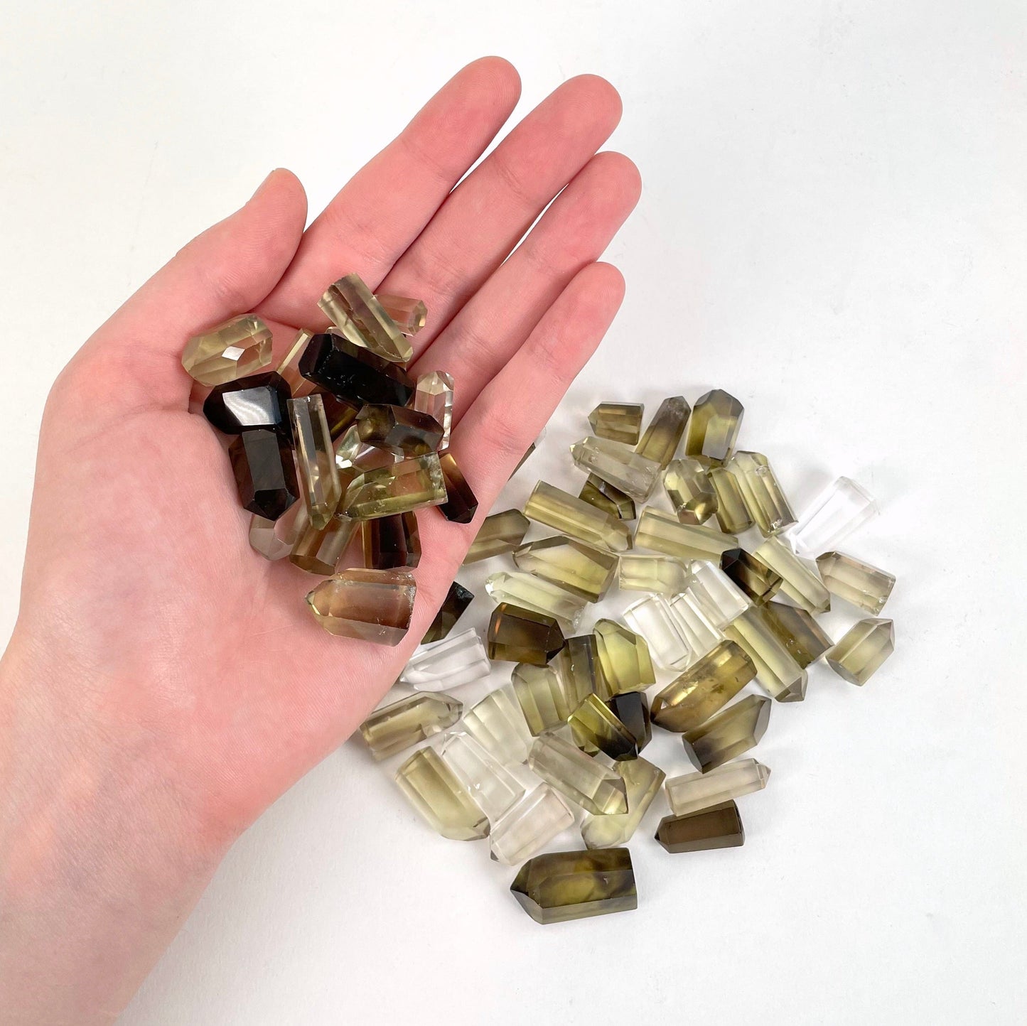 Natural citrine points in a hand and more on a white background.