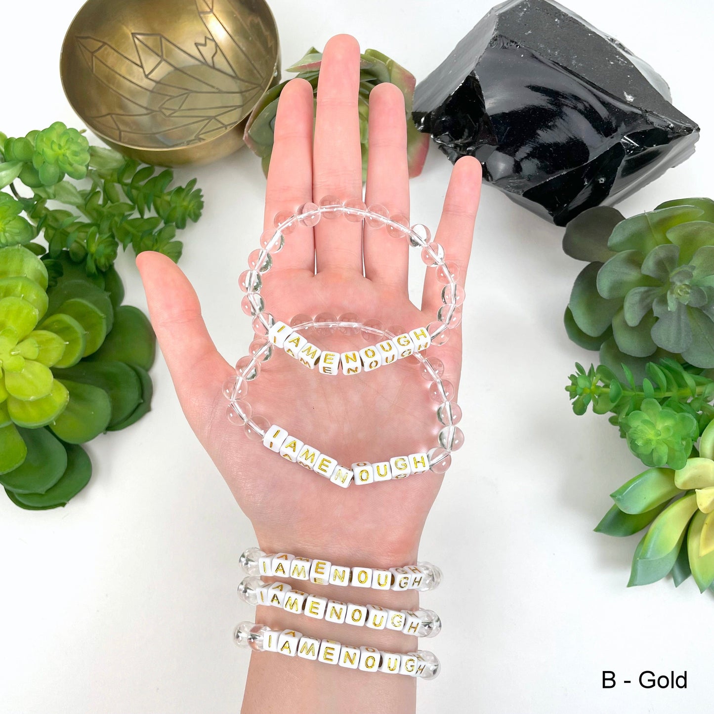 gold "IAMENOUGH" letter beads in hand and on wrist for color reference