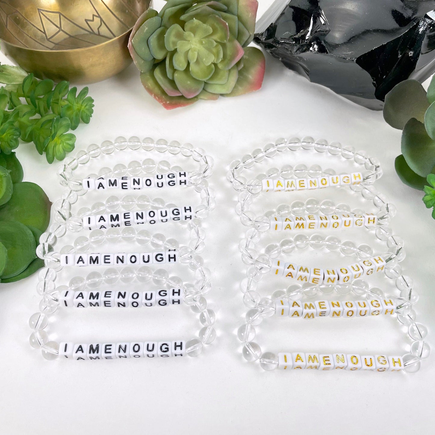 black "IAMENOUGH" letter bead bracelet option on left display and gold "IAMENOUGH" letter bead bracelet option on right display 