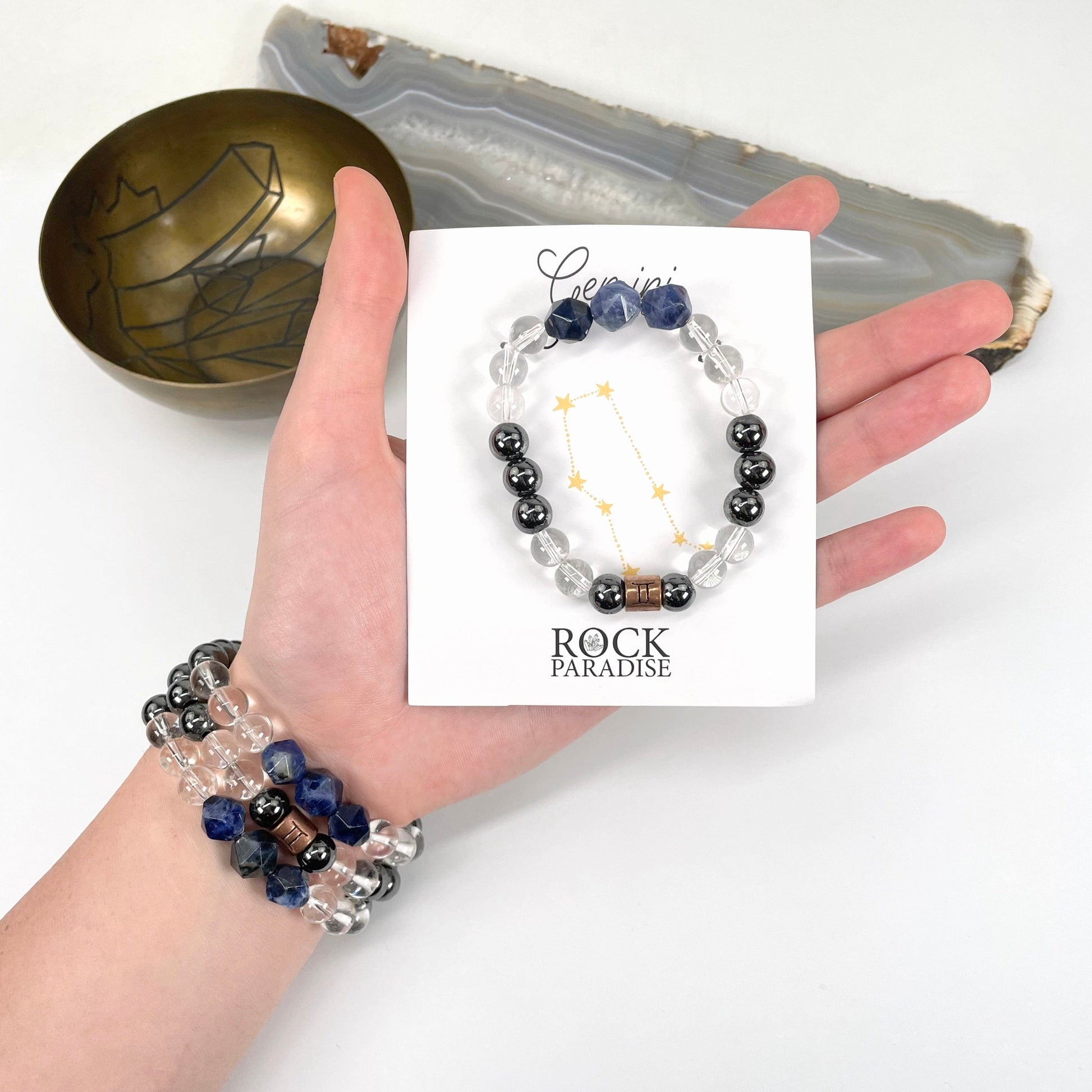 packaged gemini zodiac bracelet in hand with gemini zodiac bracelets on wrist