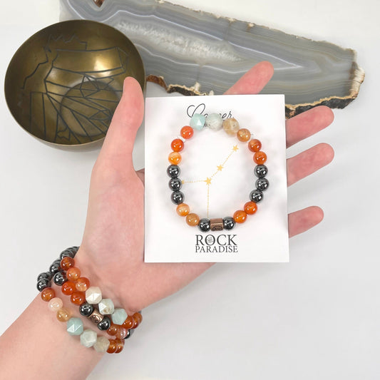 packaged cancer zodiac bracelet in hand with cancer zodiac bracelets on wrist